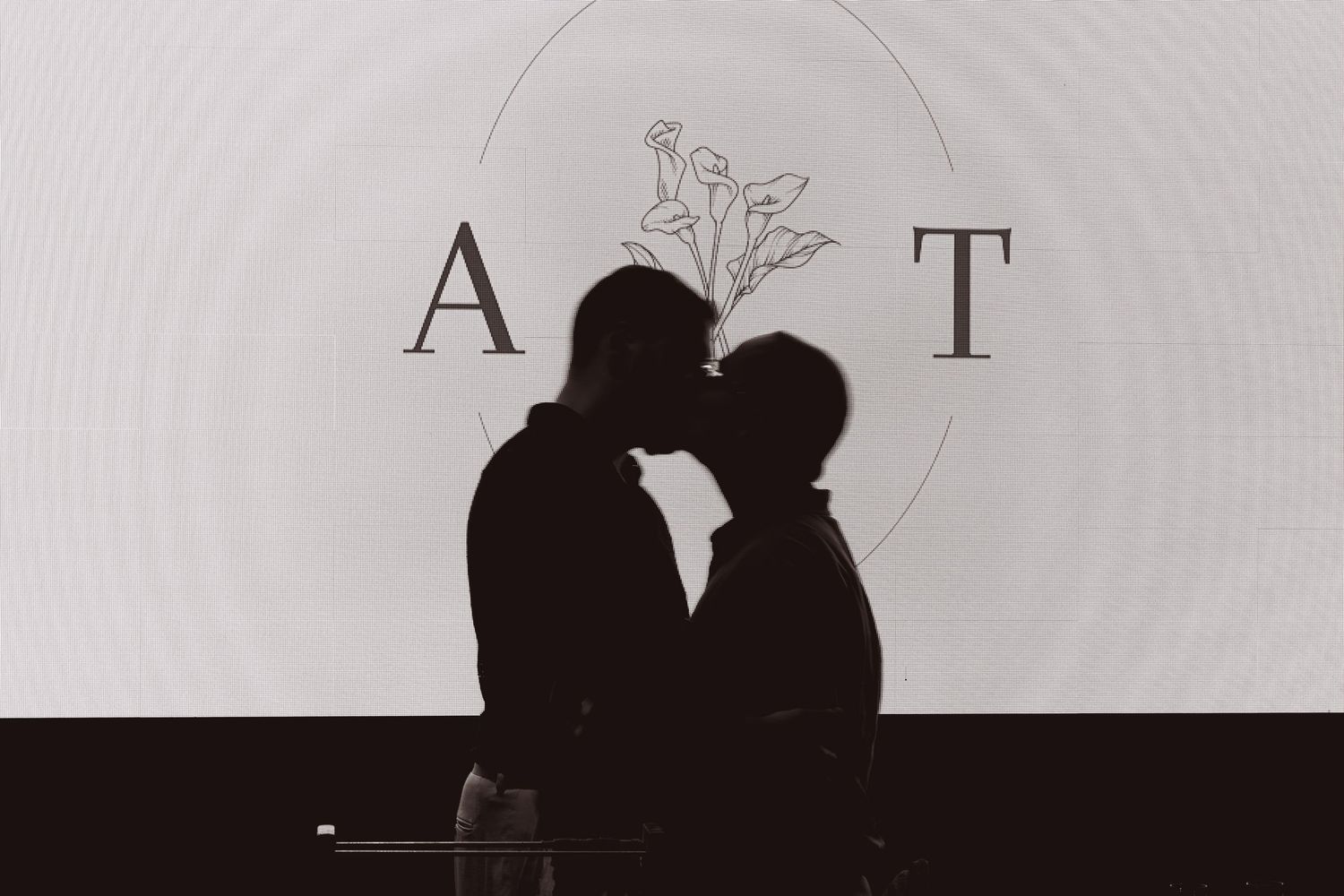 Silhouetted figures stand in front of a bright white background creating a dramatic contrast effect.