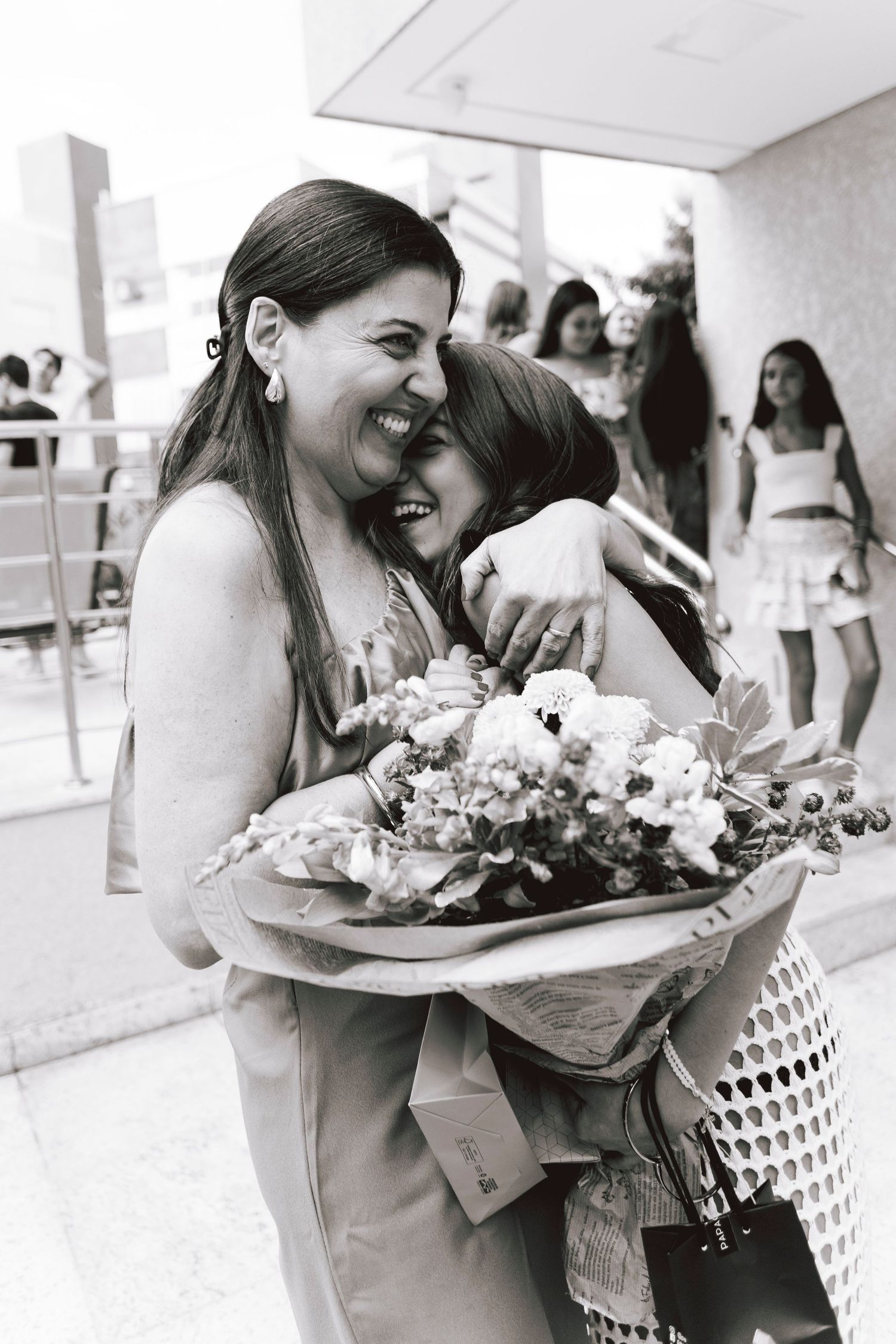 Woman smiling with joy while holding flower bouquet during celebratory moment.