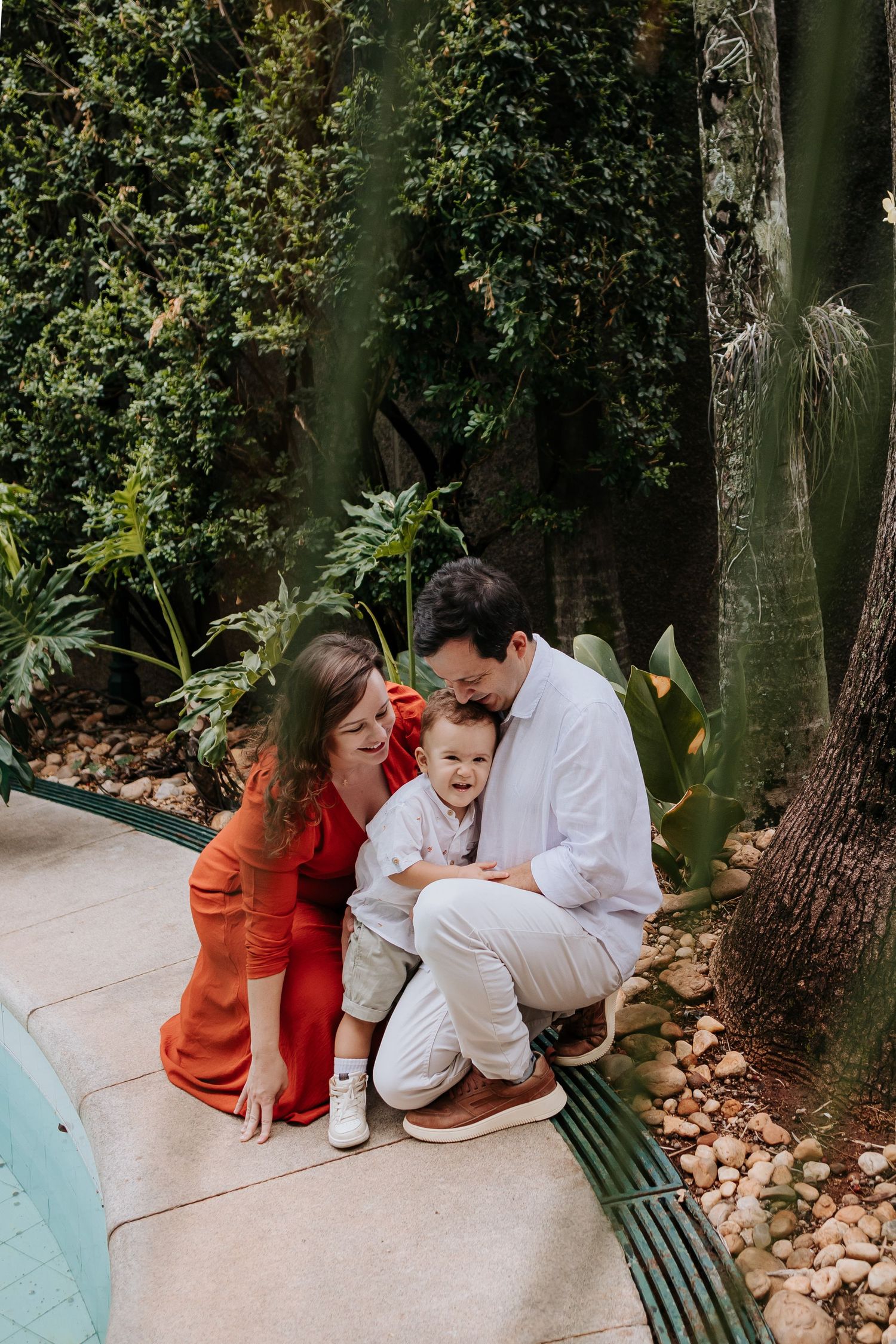 Family sharing an intimate moment together on a garden path surrounded by lush greenery.
