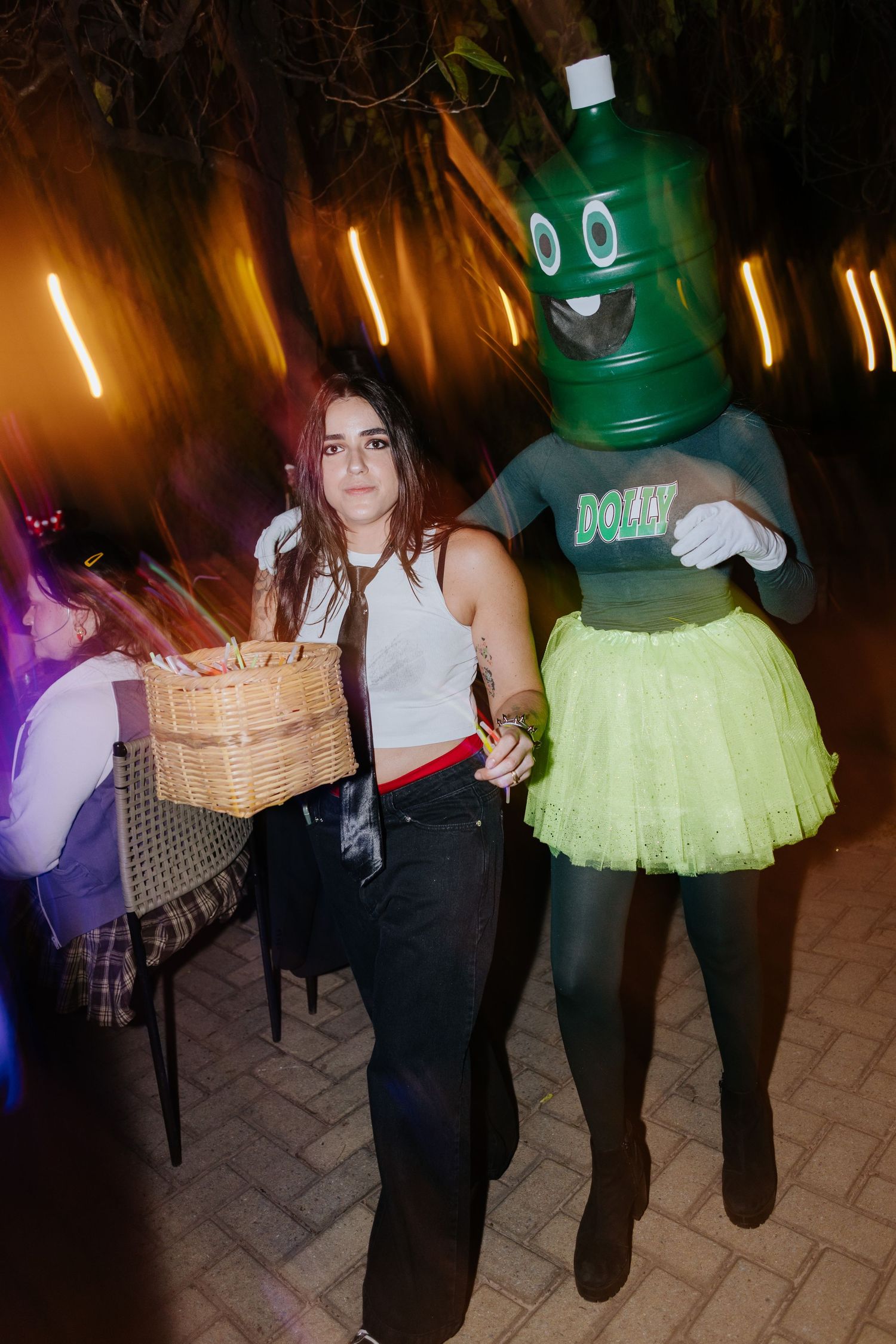 People walking in a dimly lit area carrying baskets and wearing festive outfits with colorful lighting effects.
