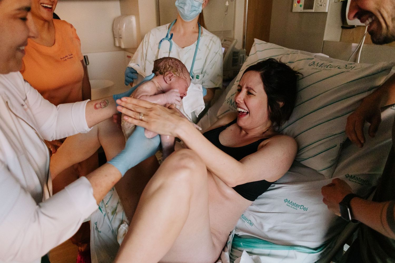 Emotional mother receiving newborn baby after childbirth in hospital room.