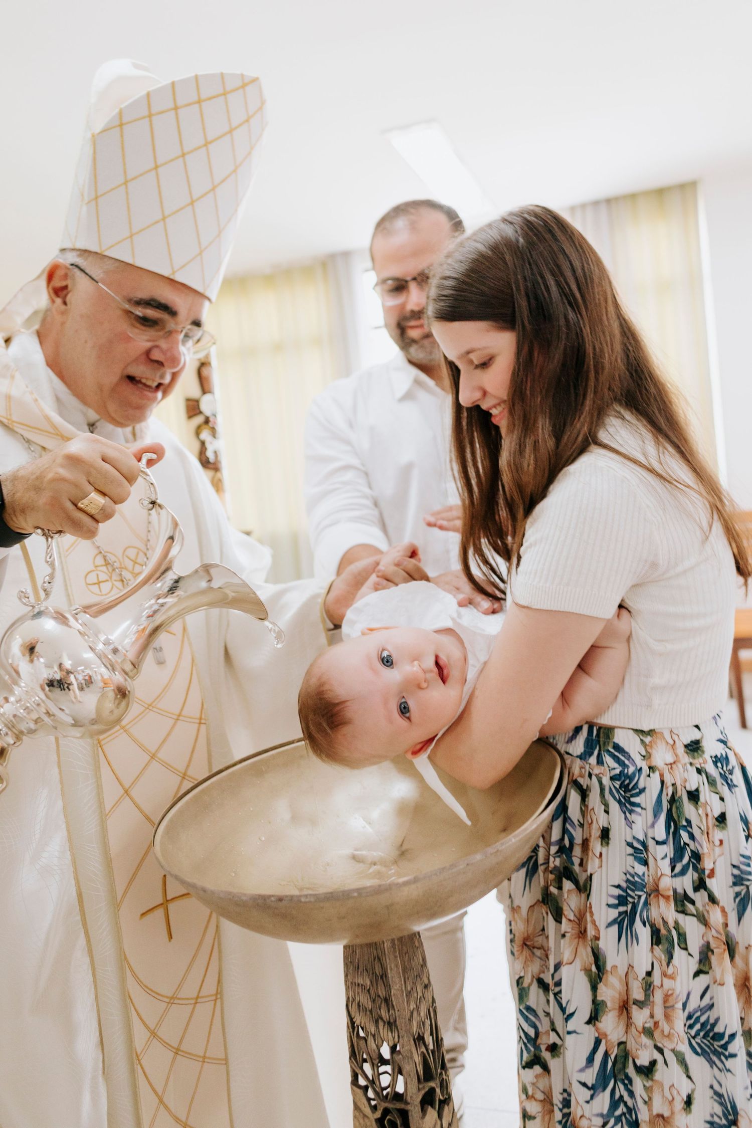 A baby being baptized in a church font during a traditional religious ceremony.
