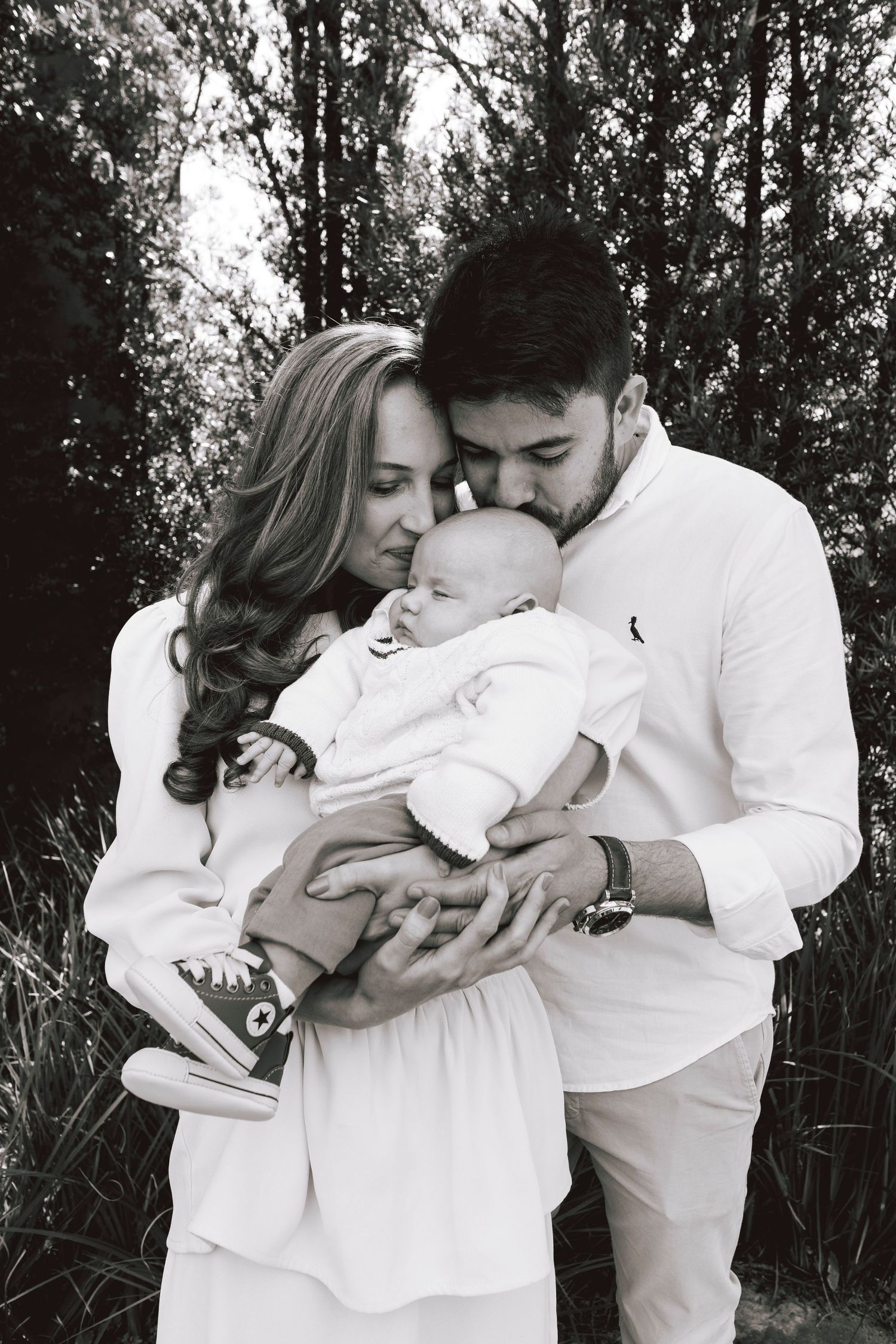 Black and white photo series showing a tender embrace between two people in white clothing against a natural backdrop.