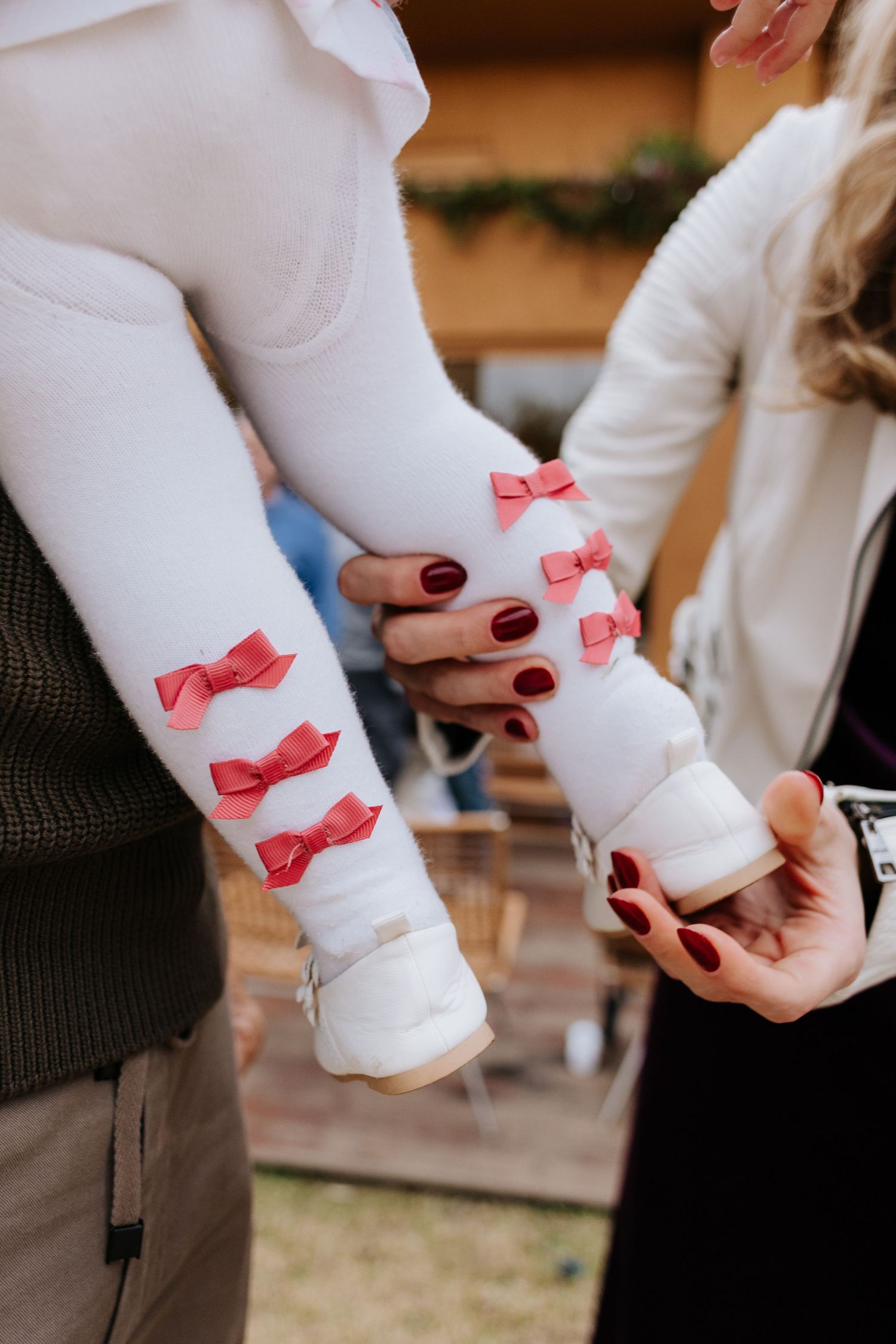 A series of photos showing hands attaching small pink bow decorations to white shirt cuffs.