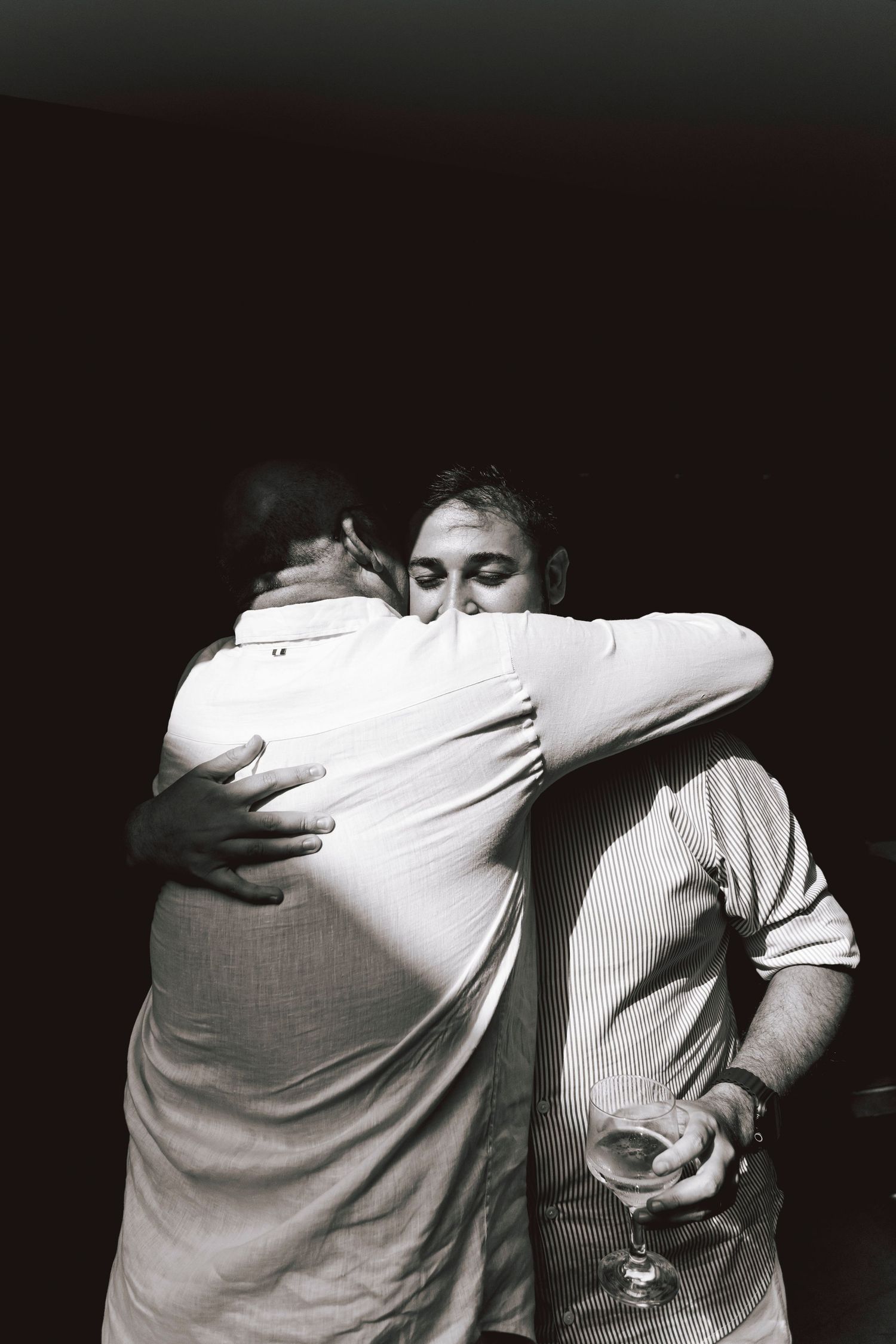 Two people sharing an emotional embrace at a social gathering.