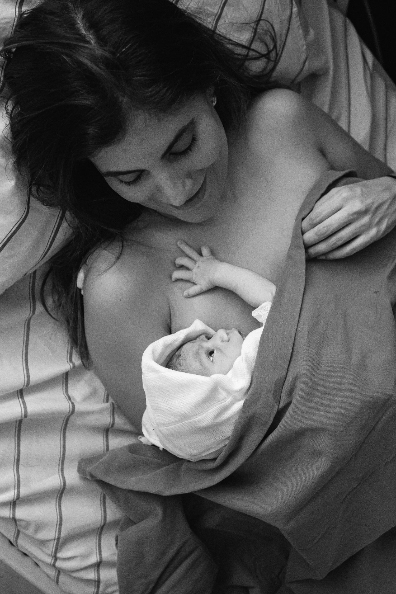 A black and white image of skin-to-skin contact with a newborn baby.