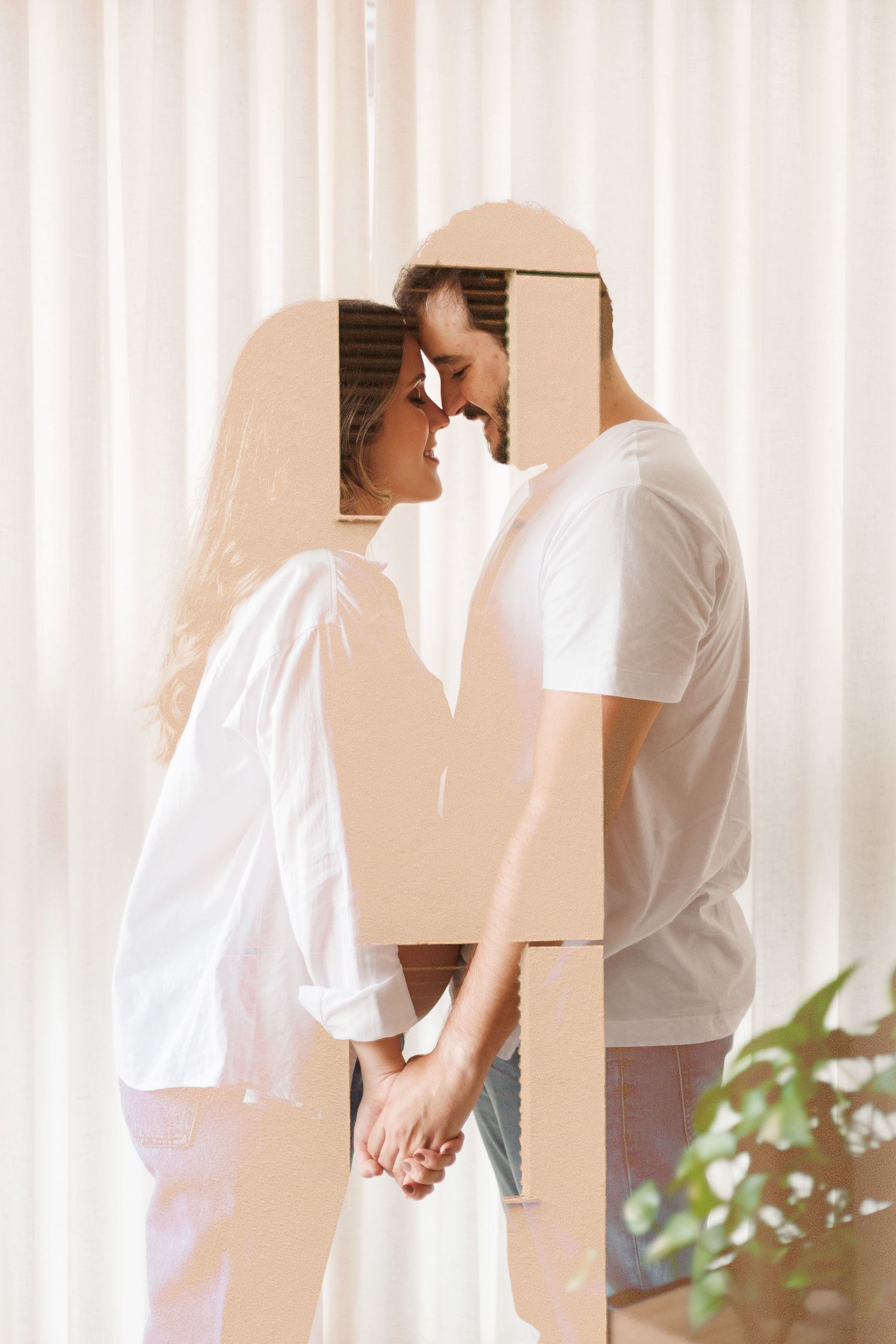 Romantic couple holding hands and touching foreheads while moving into new home with cardboard boxes.