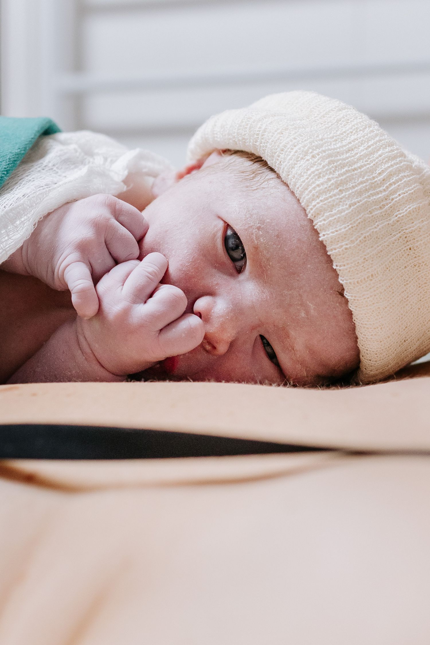 A series of close-up photos showing a baby wrapped in a cream-colored blanket lying down.