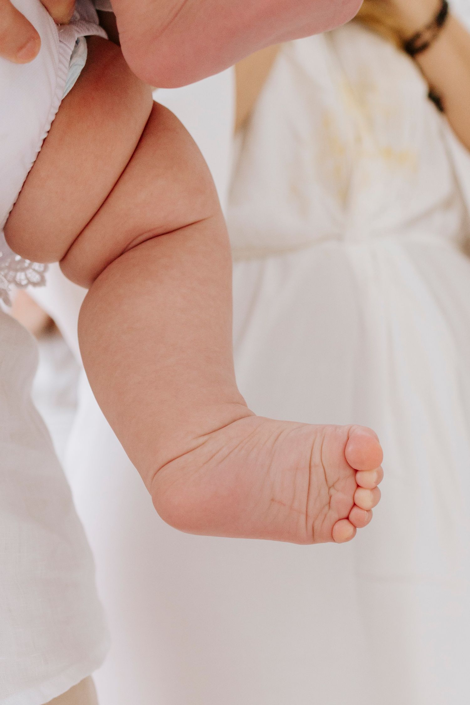 Close-up of baby's tiny foot against white fabric background.