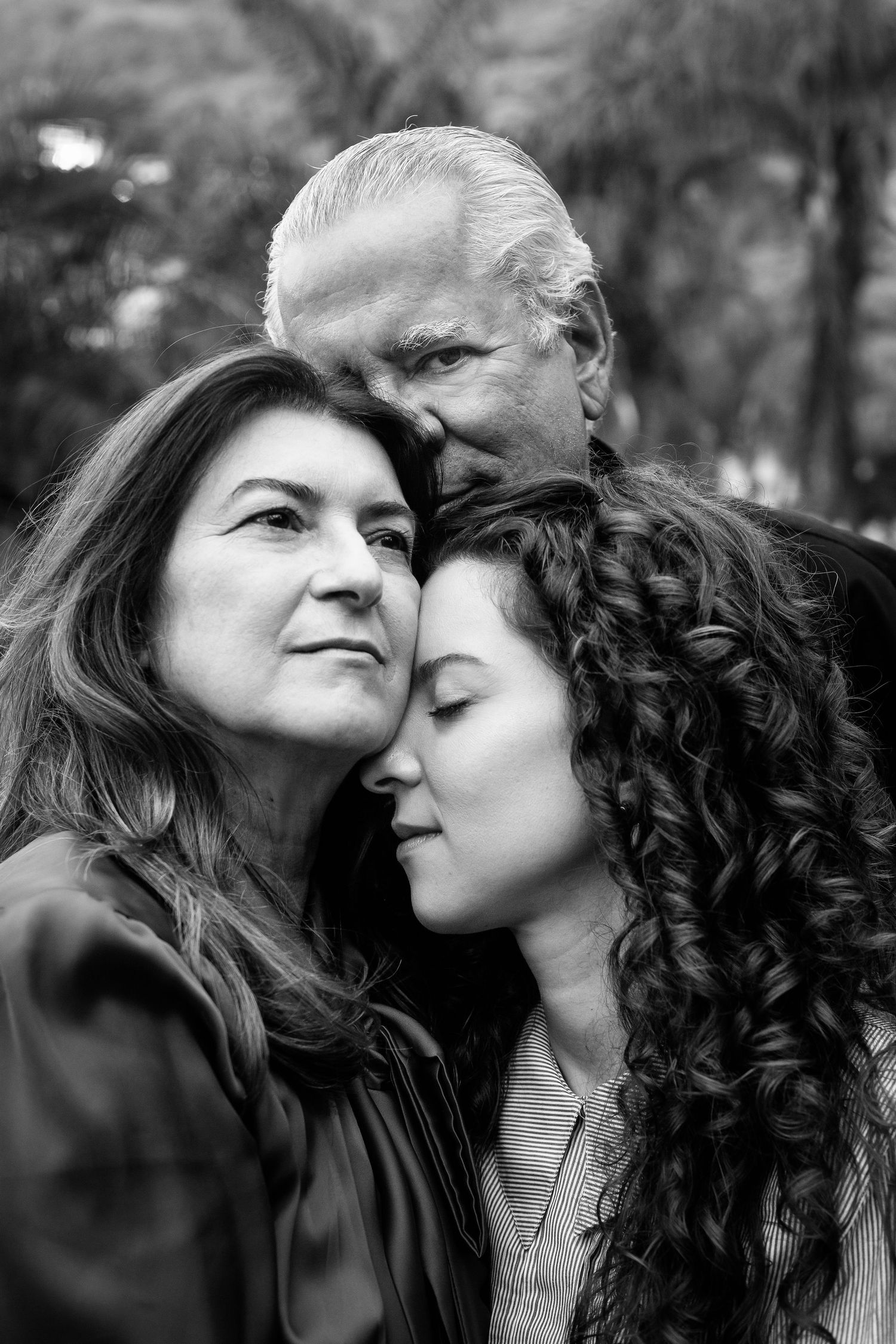 Three generations pose together in an intimate black and white outdoor portrait.