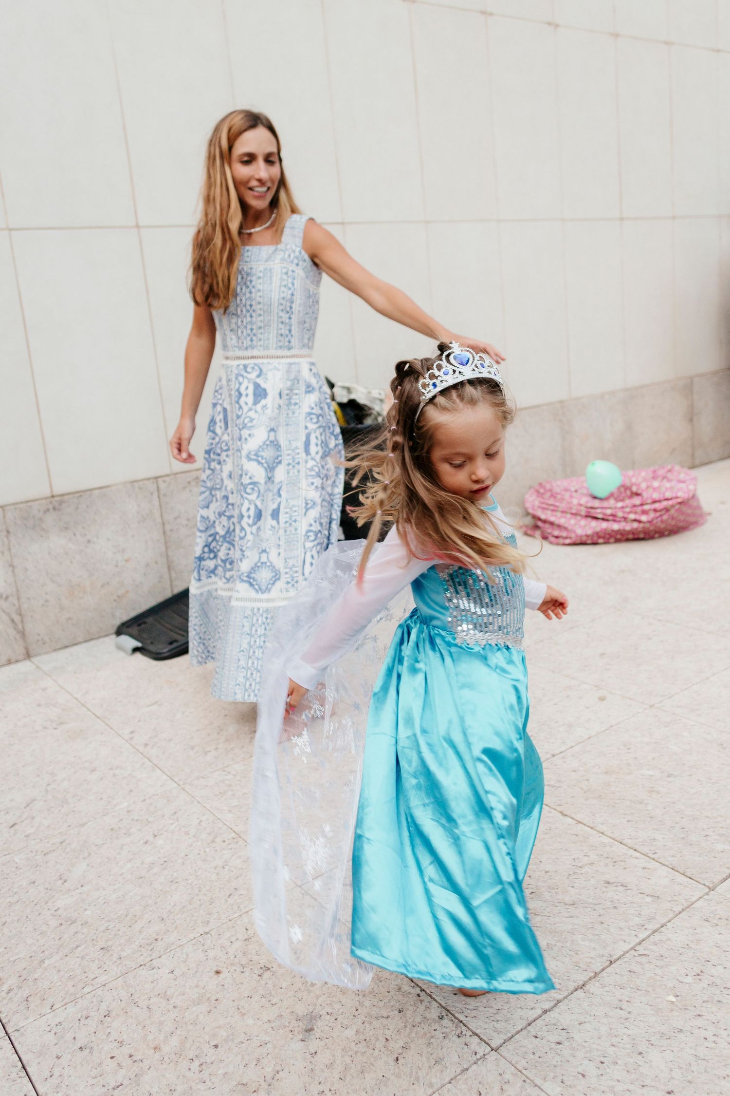 Two people in fancy blue and white formal dresses dancing together.