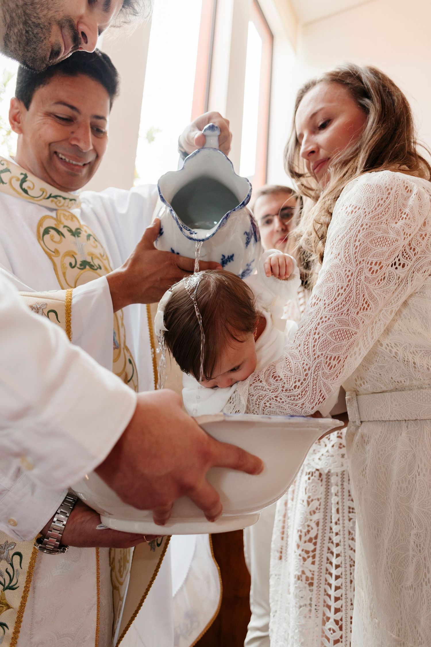 Baby baptism ceremony with priest pouring holy water during traditional Christian ritual.