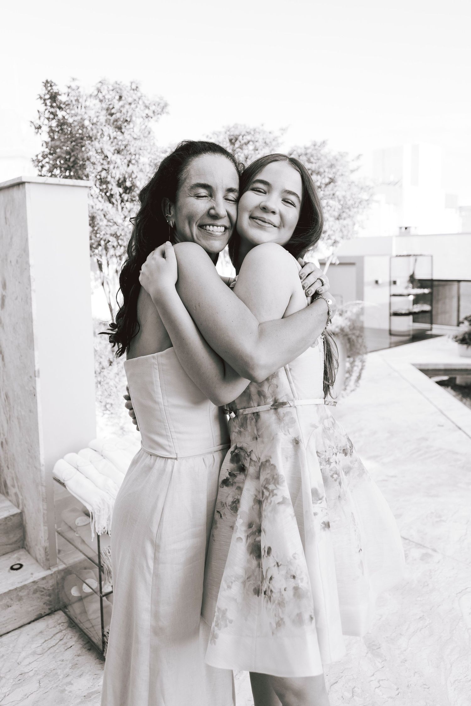 Black and white candid photo of two people embracing and laughing together outdoors.