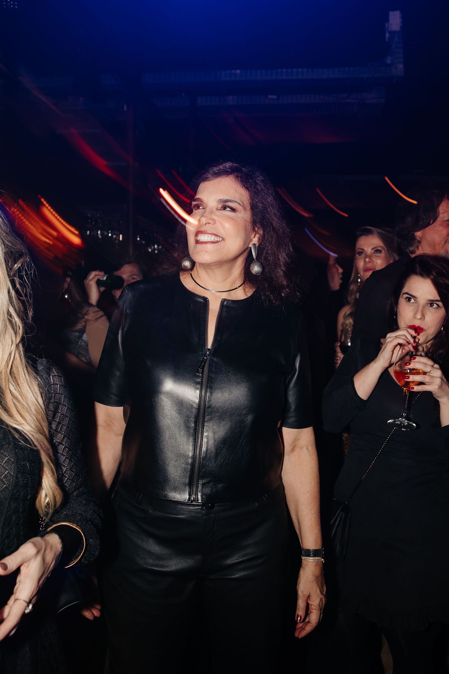 People dancing and socializing at a dimly lit nightclub with blue and red lighting.