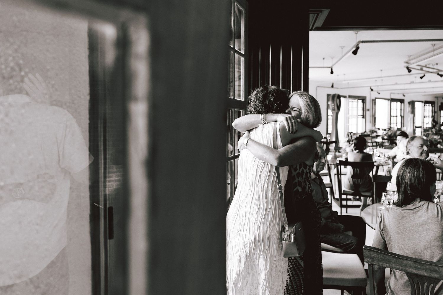 A black and white photo strip showing candid moments at a wedding reception with guests and the couple.