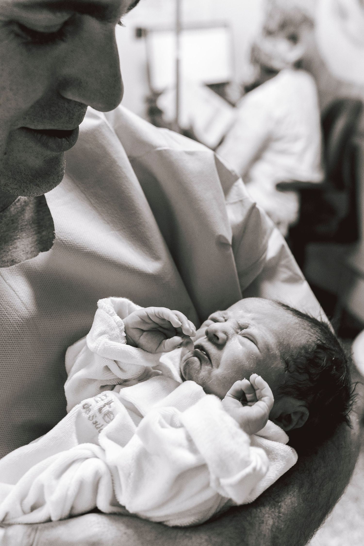Black and white portrait of a newborn baby in hospital clothing.