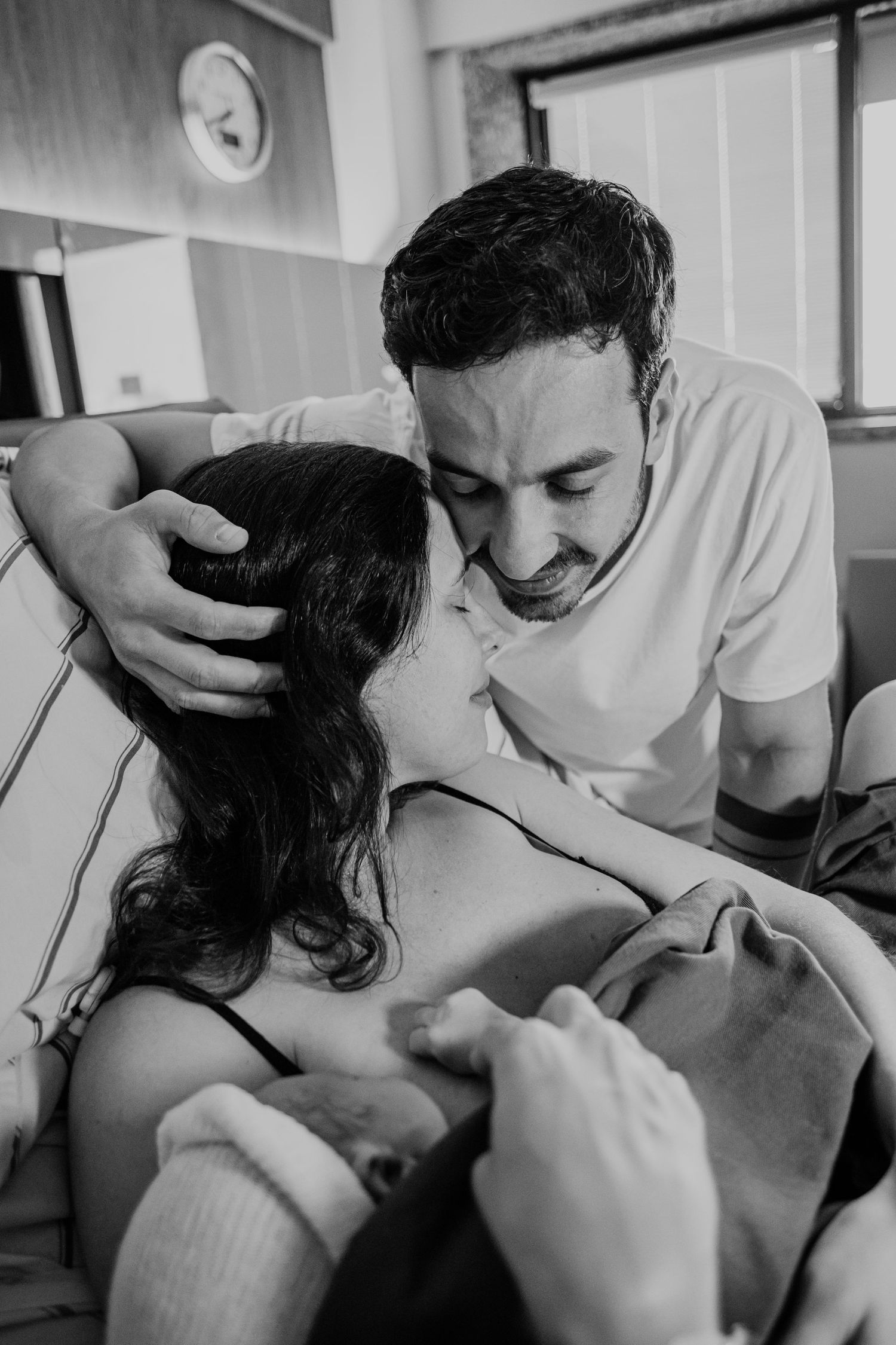 Tender moment captured between couple in hospital room showing loving connection.