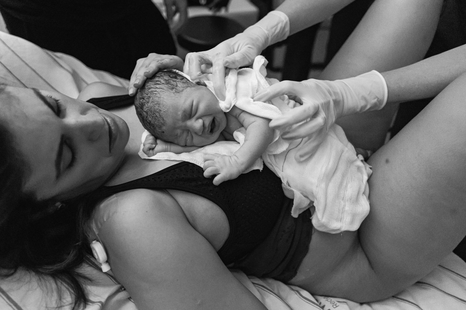 A black and white image capturing the first moments after birth in a medical setting.