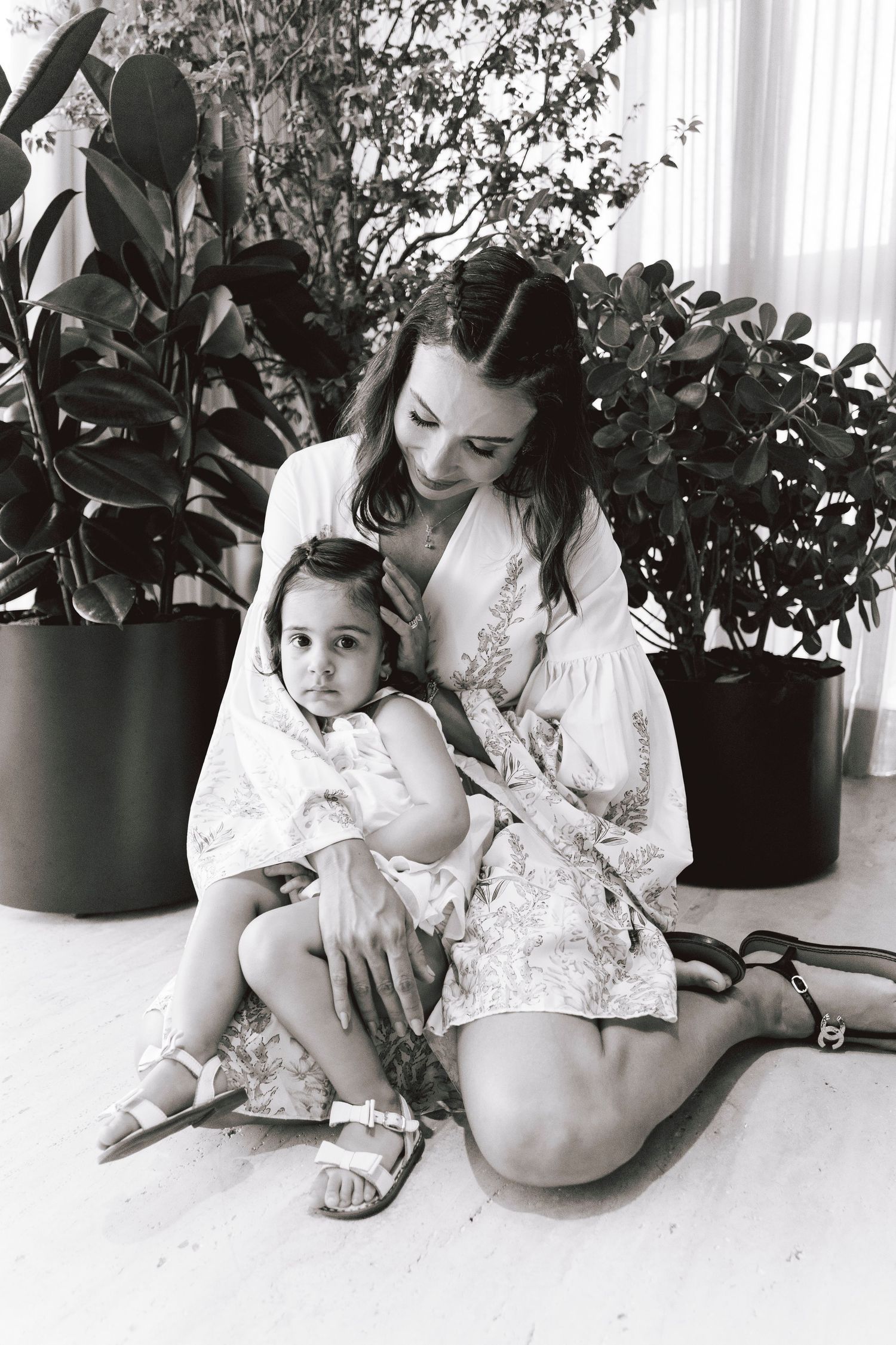 Black and white portrait in an indoor setting with potted plants.