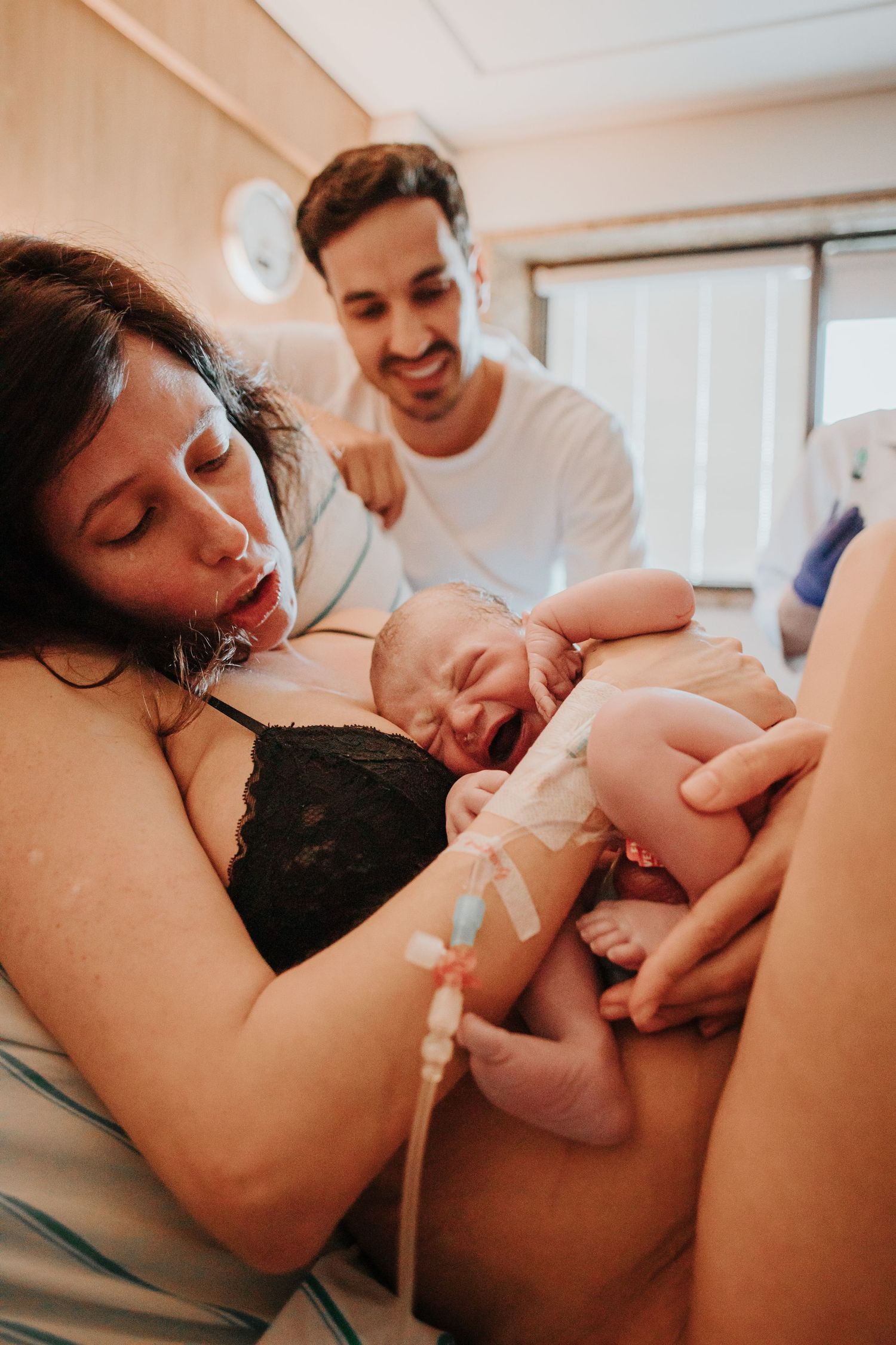 Intimate hospital room scene showing first moments with newborn after delivery.