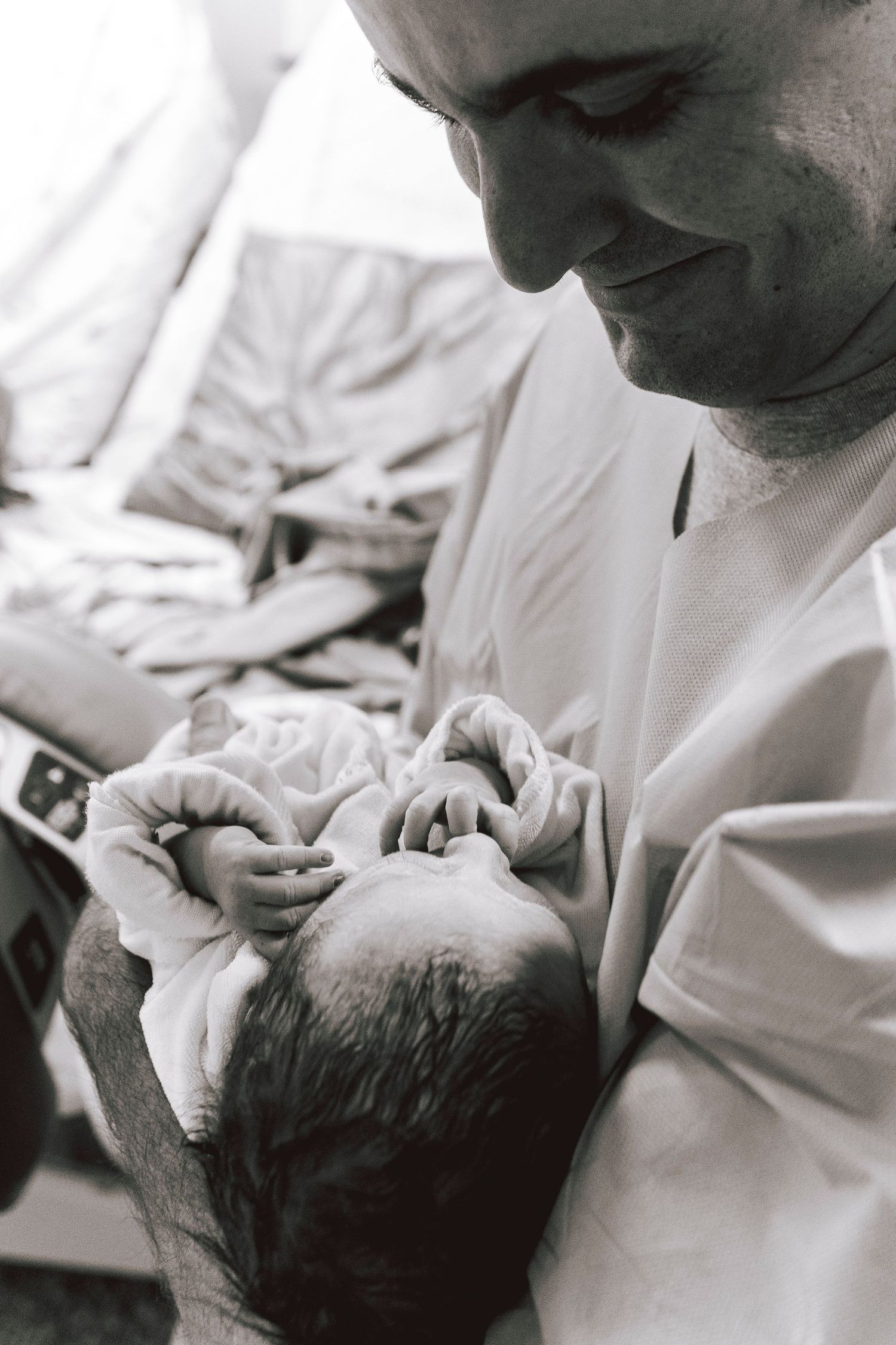 Intimate black and white moment of newborn care in hospital setting.