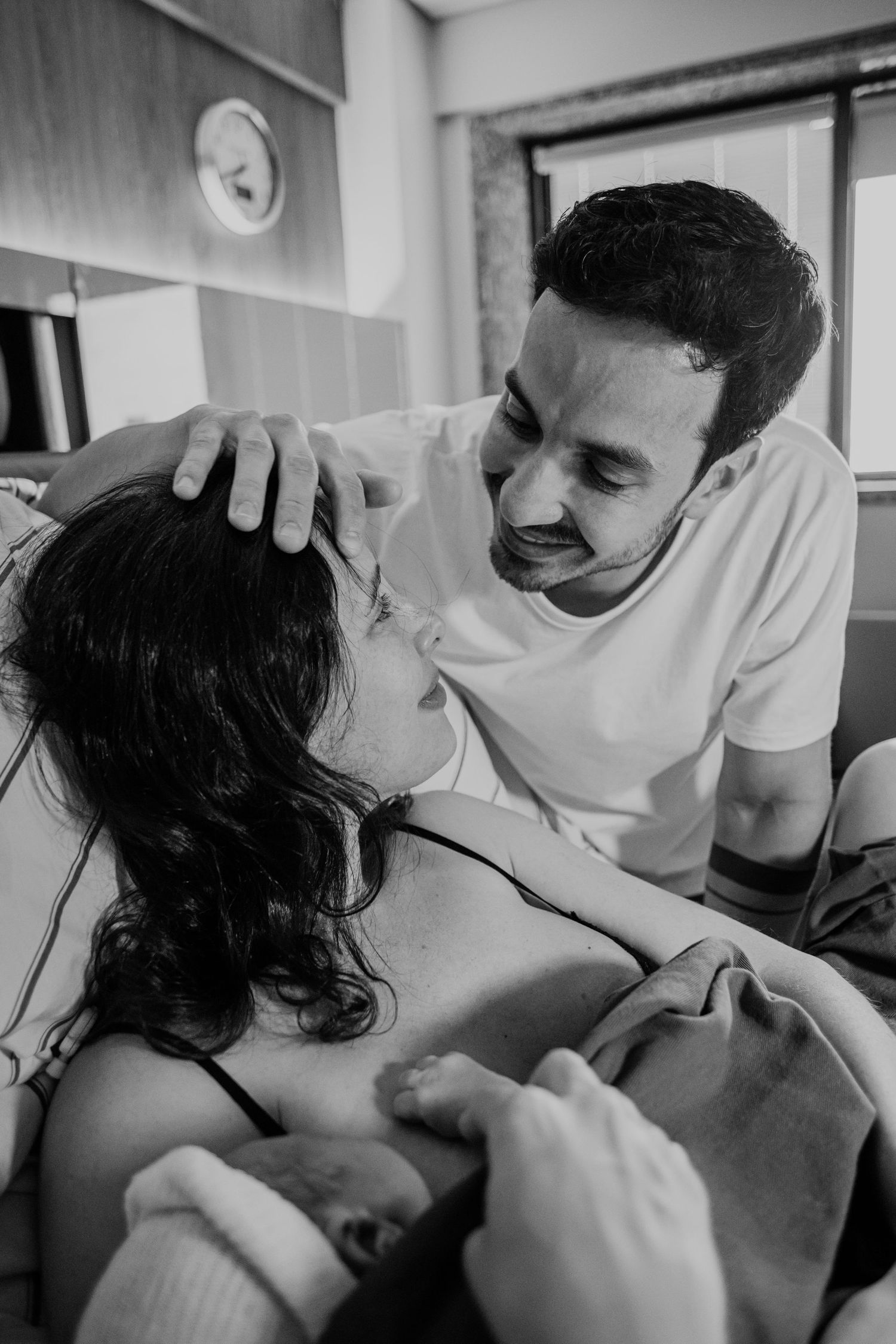 Intimate hospital room moment between couple during childbirth with emotional expressions.