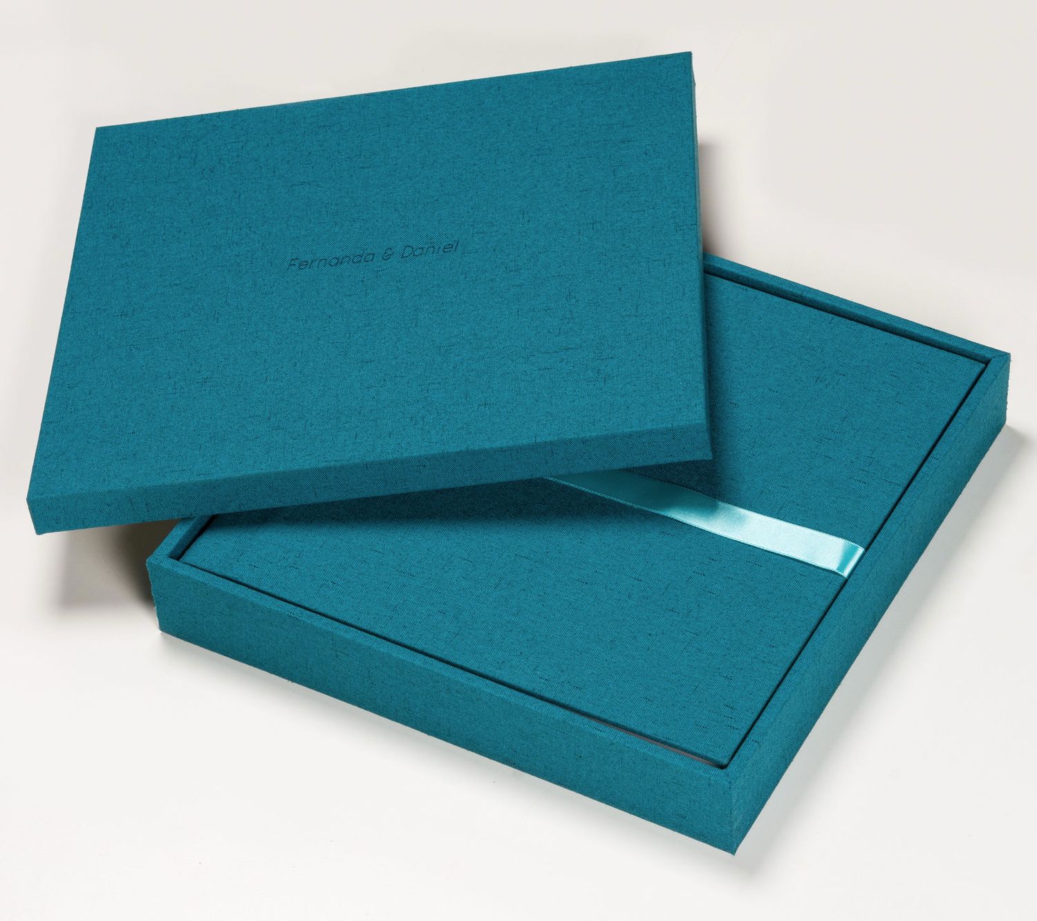 Teal linen keepsake box with lid, featuring a satin ribbon accent, perfect for storing photos or gifts.