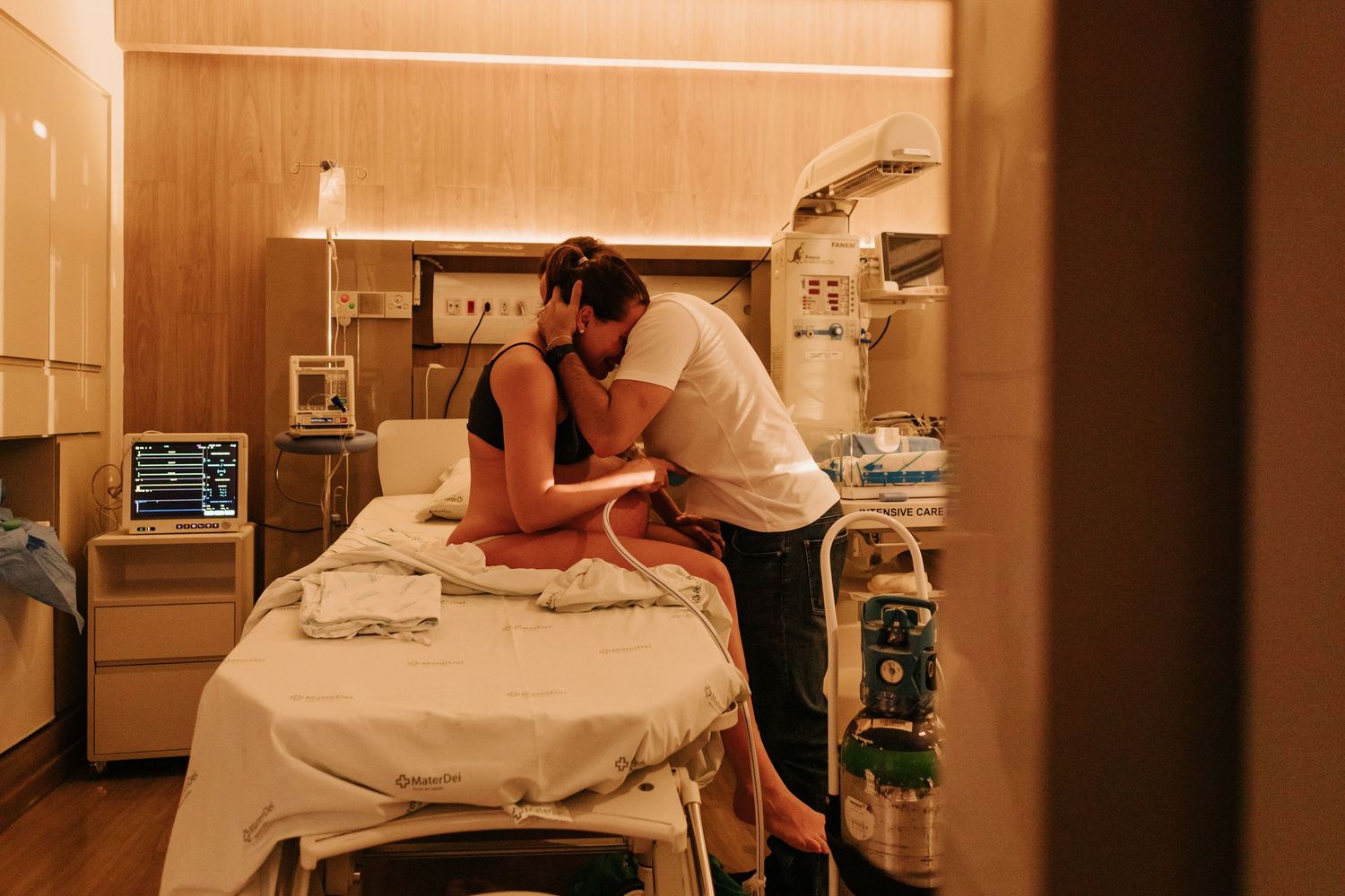 Tender moment in warm-lit hospital delivery room.
