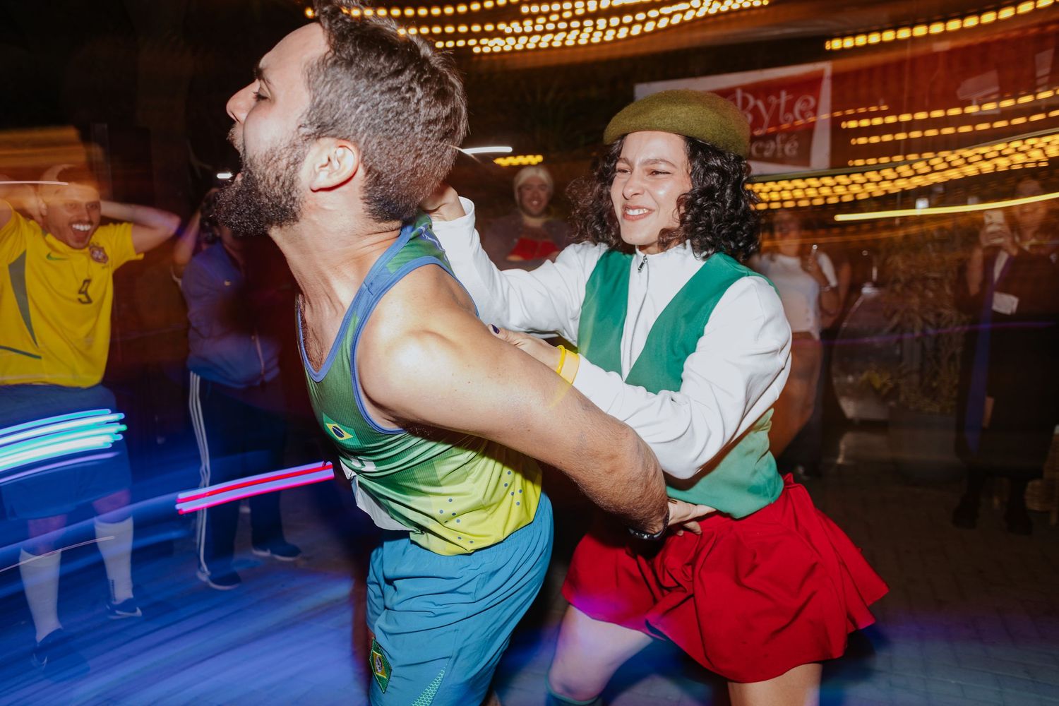 People dancing and having fun at a lively party with string lights overhead.
