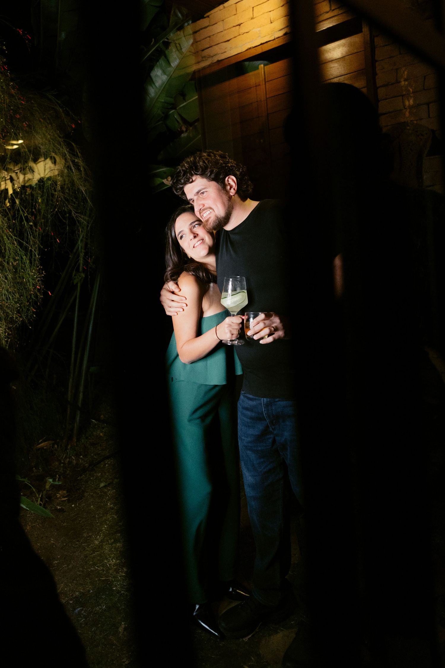 A couple shares a romantic moment at night against a dimly lit wall in a series of intimate poses.