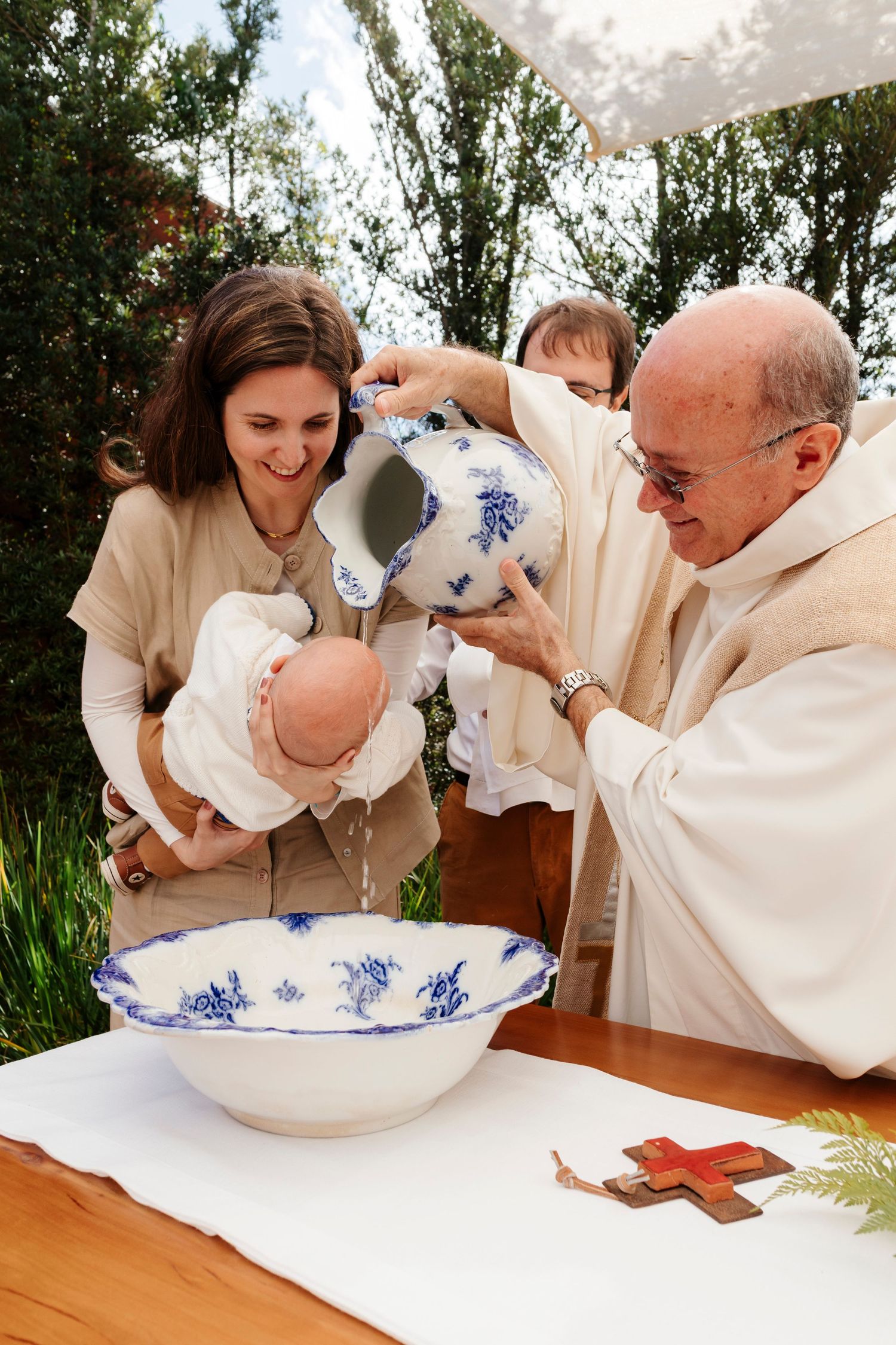 A sequence of photos showing a Christian baptism ceremony being performed at a wooden table outdoors.