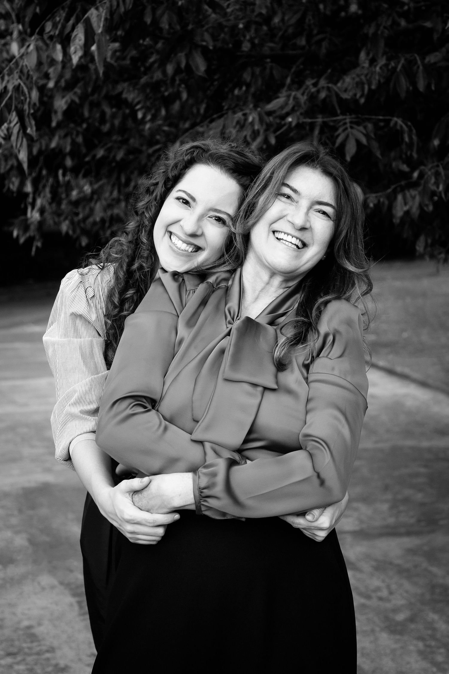 Two people share a joyful laugh while embracing in this black and white outdoor portrait.