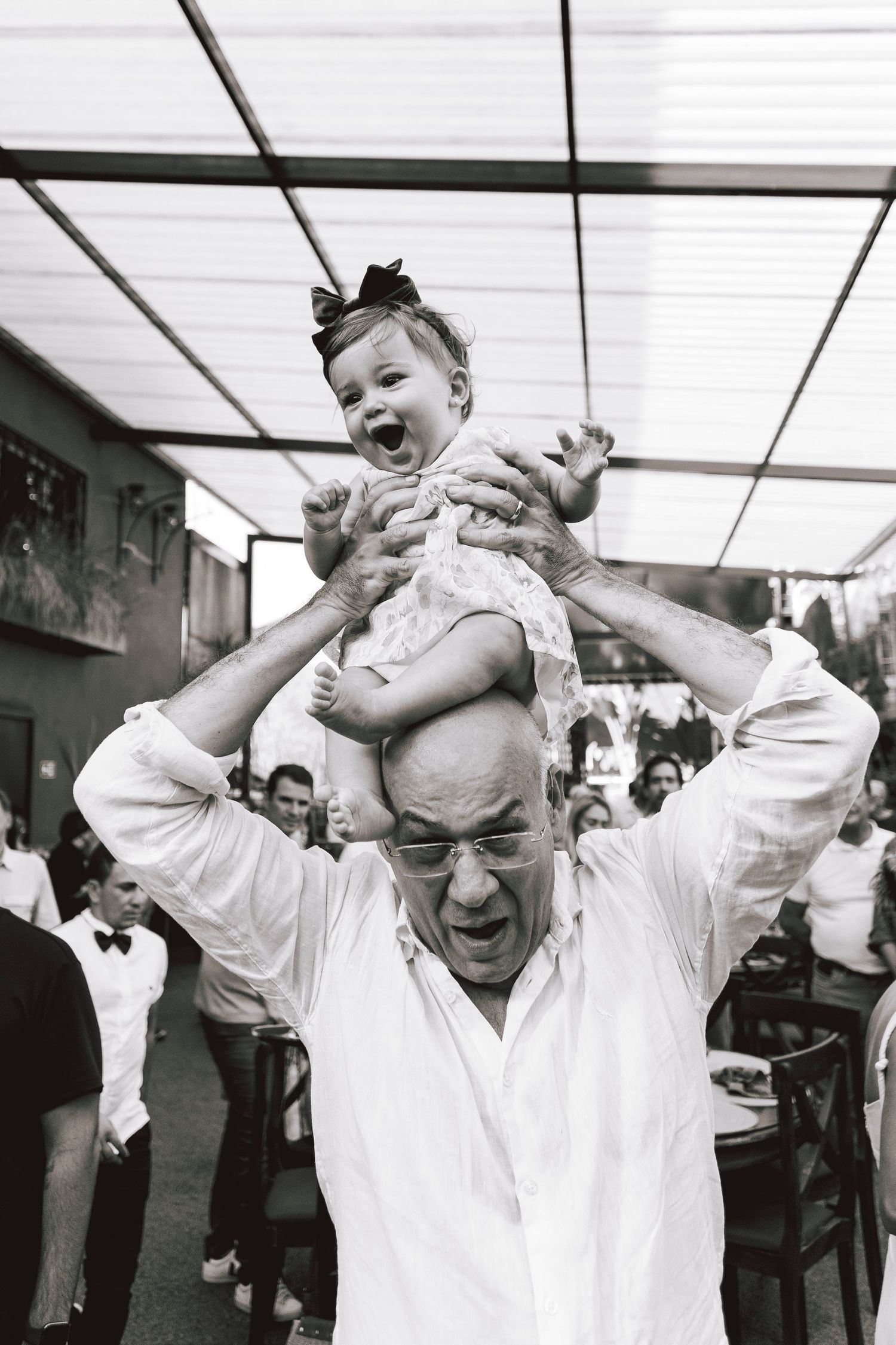 A joyful moment captured in black and white as a baby is lifted high during a celebration.