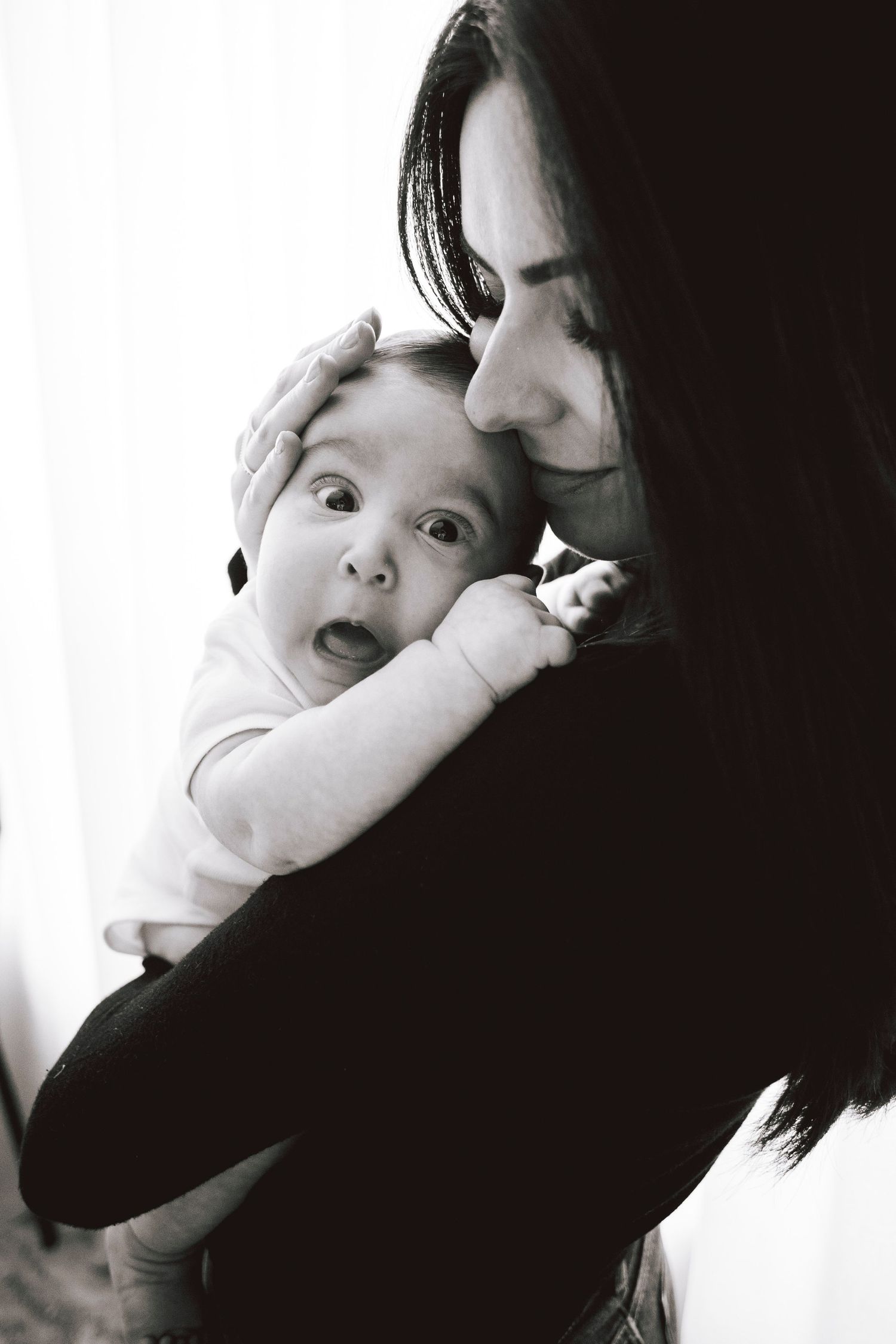Close-up black and white portrait capturing tender moment between parent and baby.