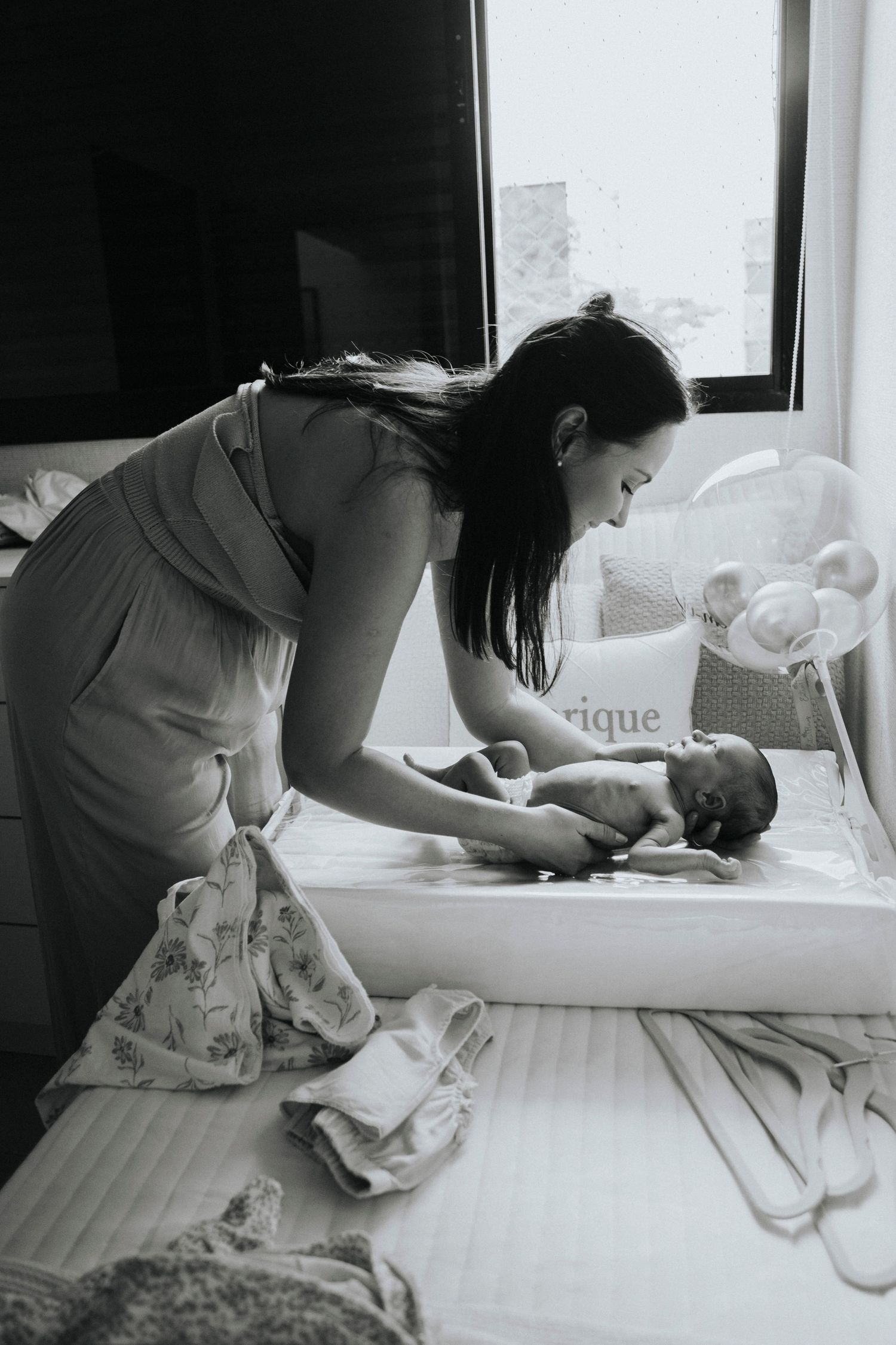 Parent tending to newborn baby on changing table in monochrome photo.