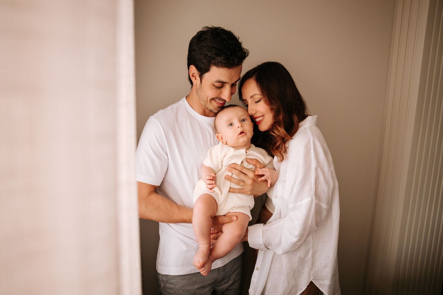 A tender moment captured in warm lighting as a couple embraces while wearing white shirts.
