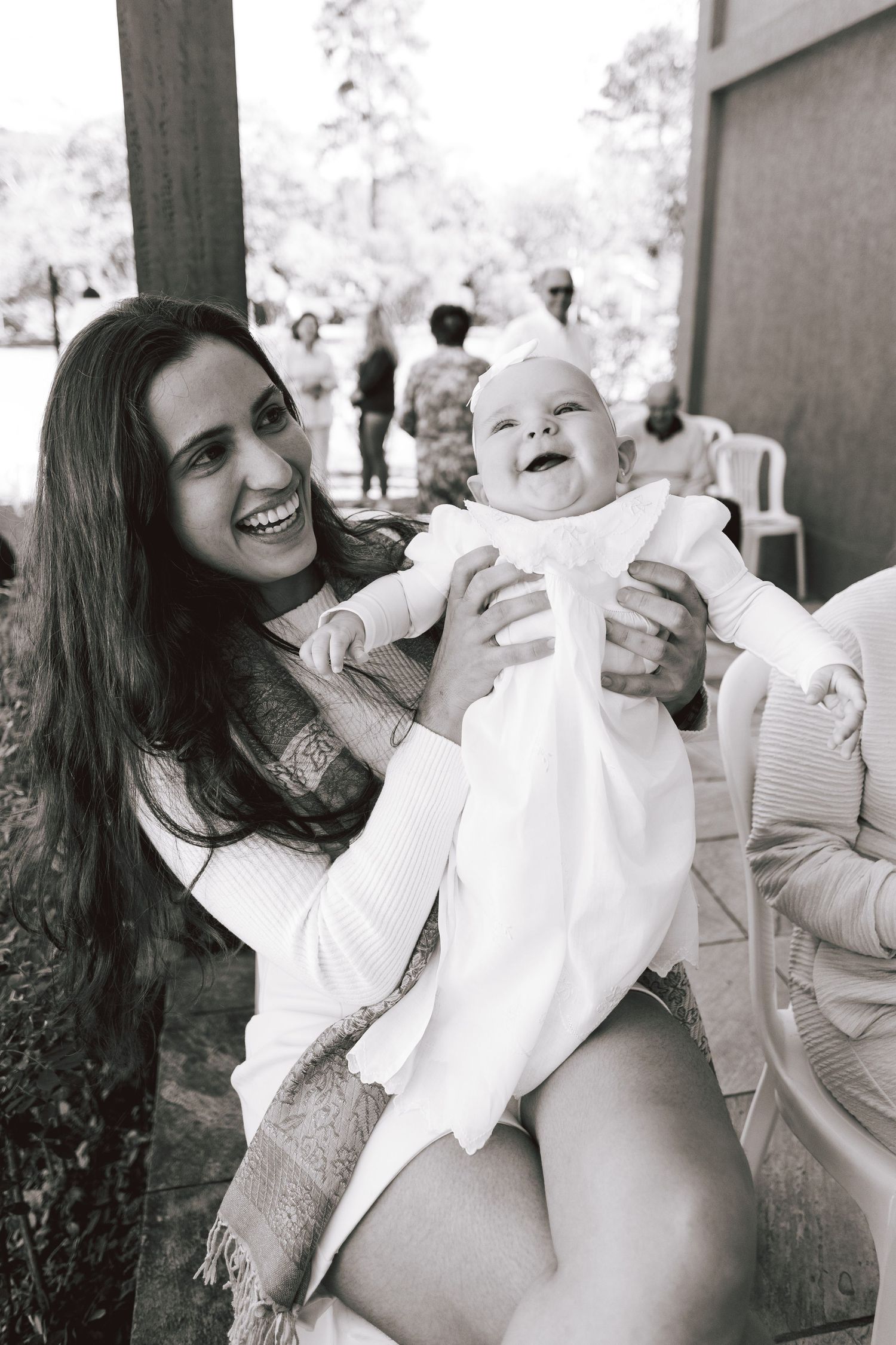 A series of joyful black and white photos showing tender moments between a parent and baby in white clothing.