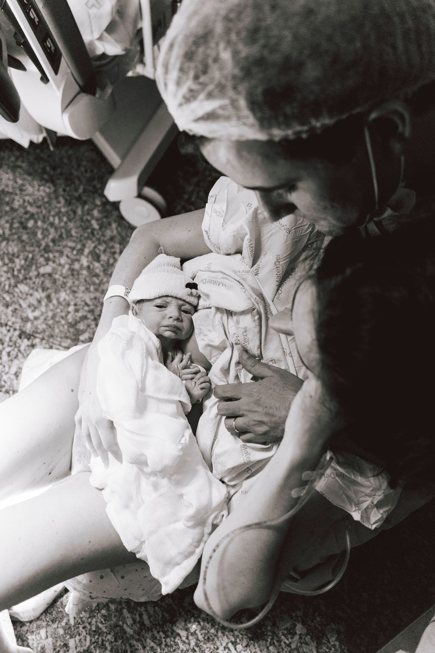 Black and white image of a newborn baby in hospital attire being cared for.