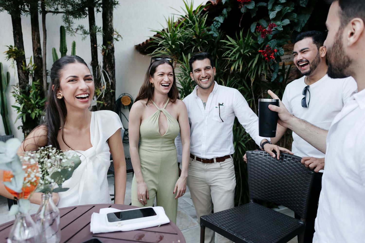 A casual outdoor gathering with friends laughing and socializing on a patio.