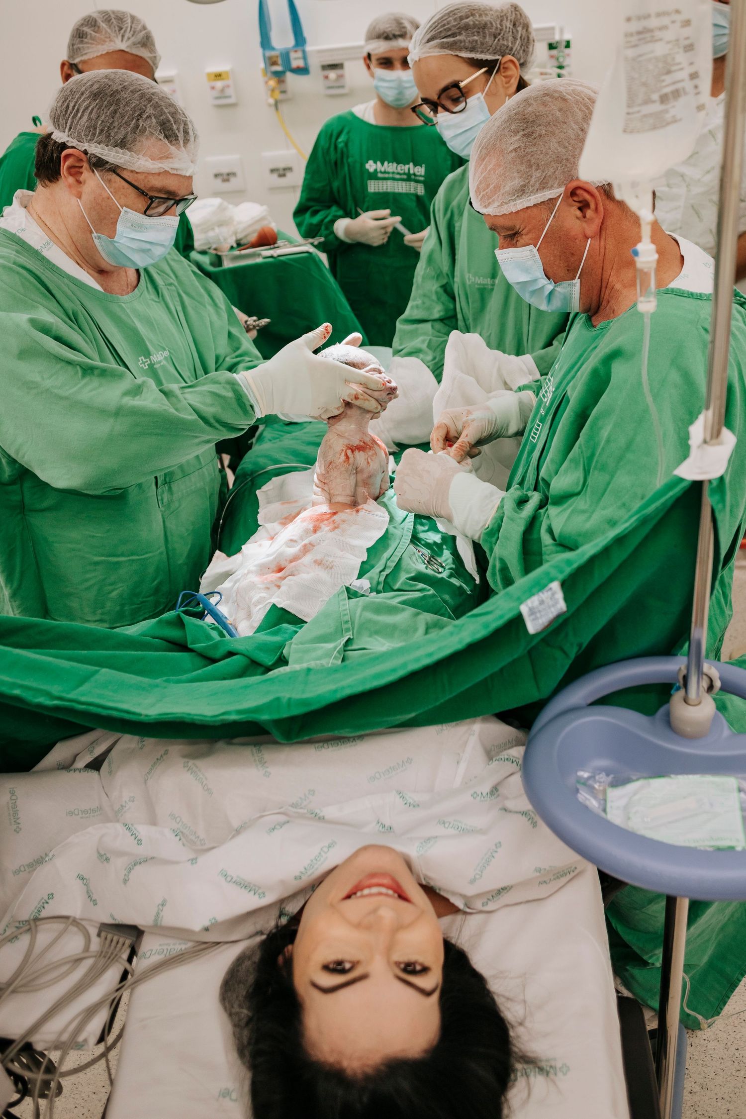 Medical team in green scrubs performs surgical procedure in operating room.