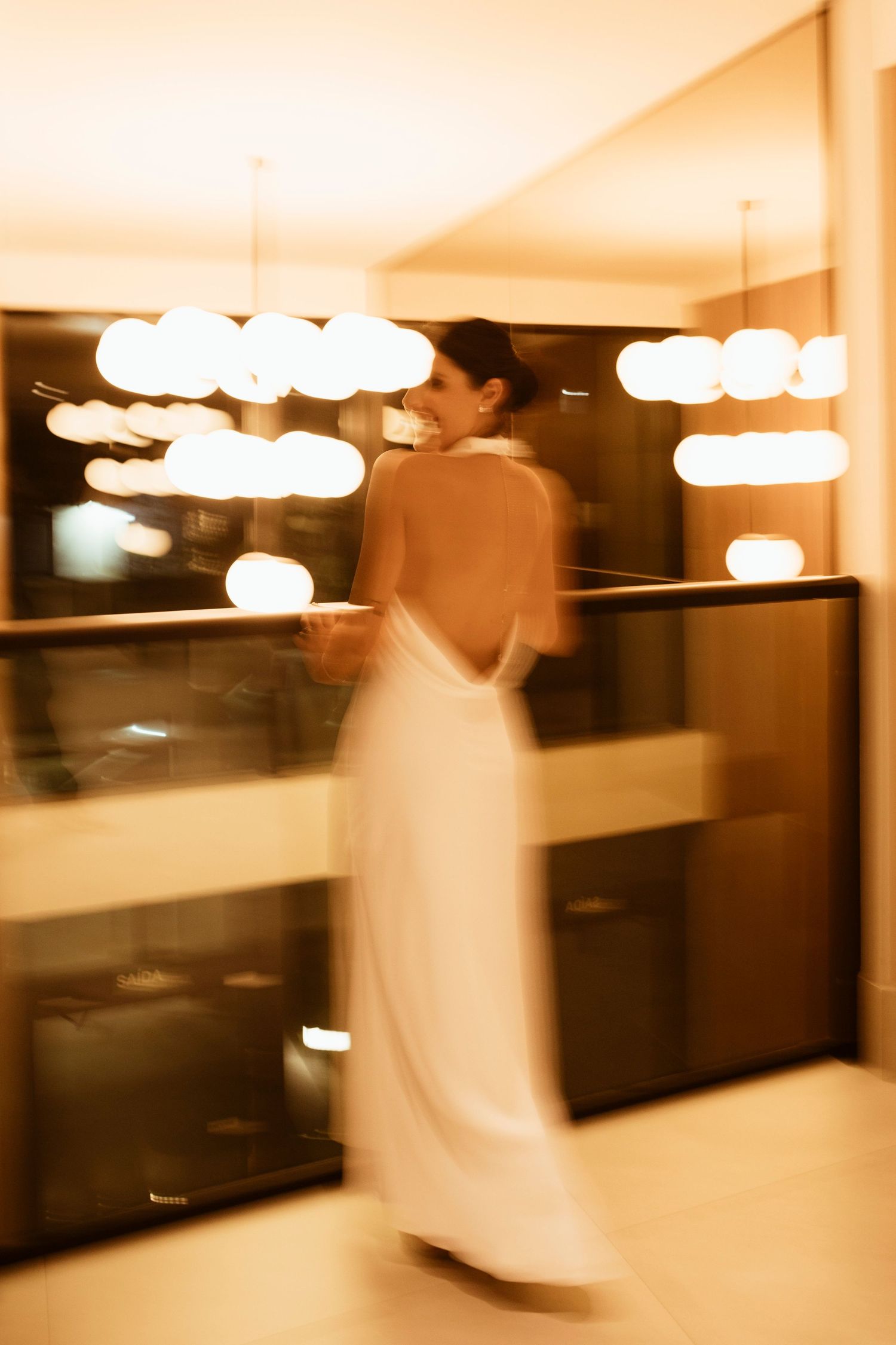 A sepia-toned sequence showing a figure in motion against a backdrop of hanging pendant lights and dark windows.