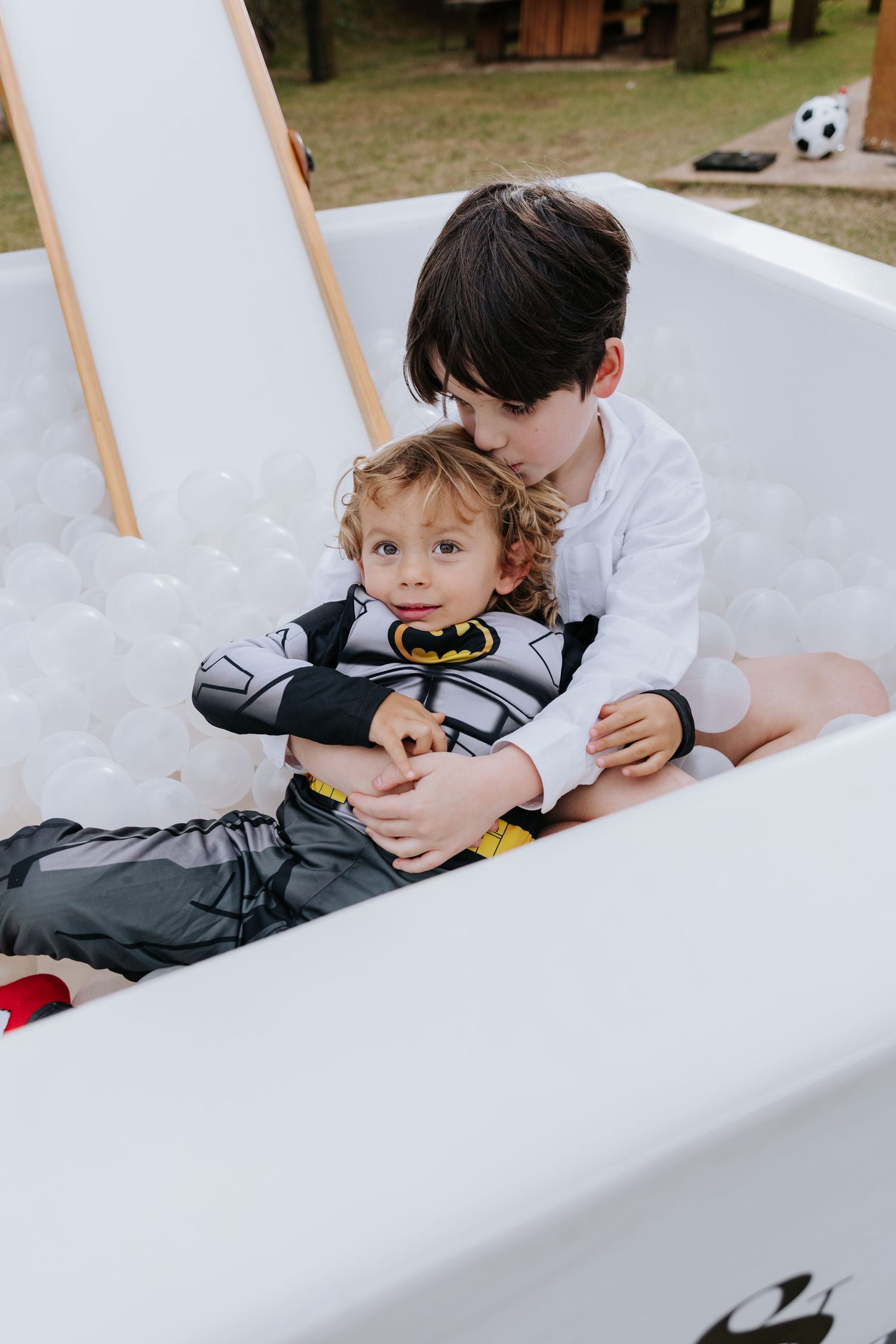 A child and adult lie together on a white couch in a series of candid, playful moments.