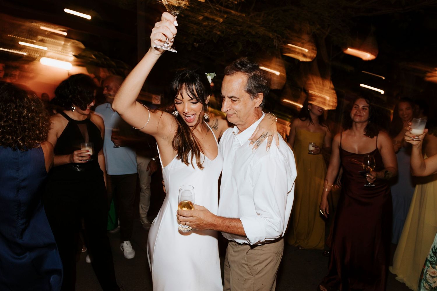 Lively dancing scene at a reception with guests celebrating on a dimly lit dance floor.