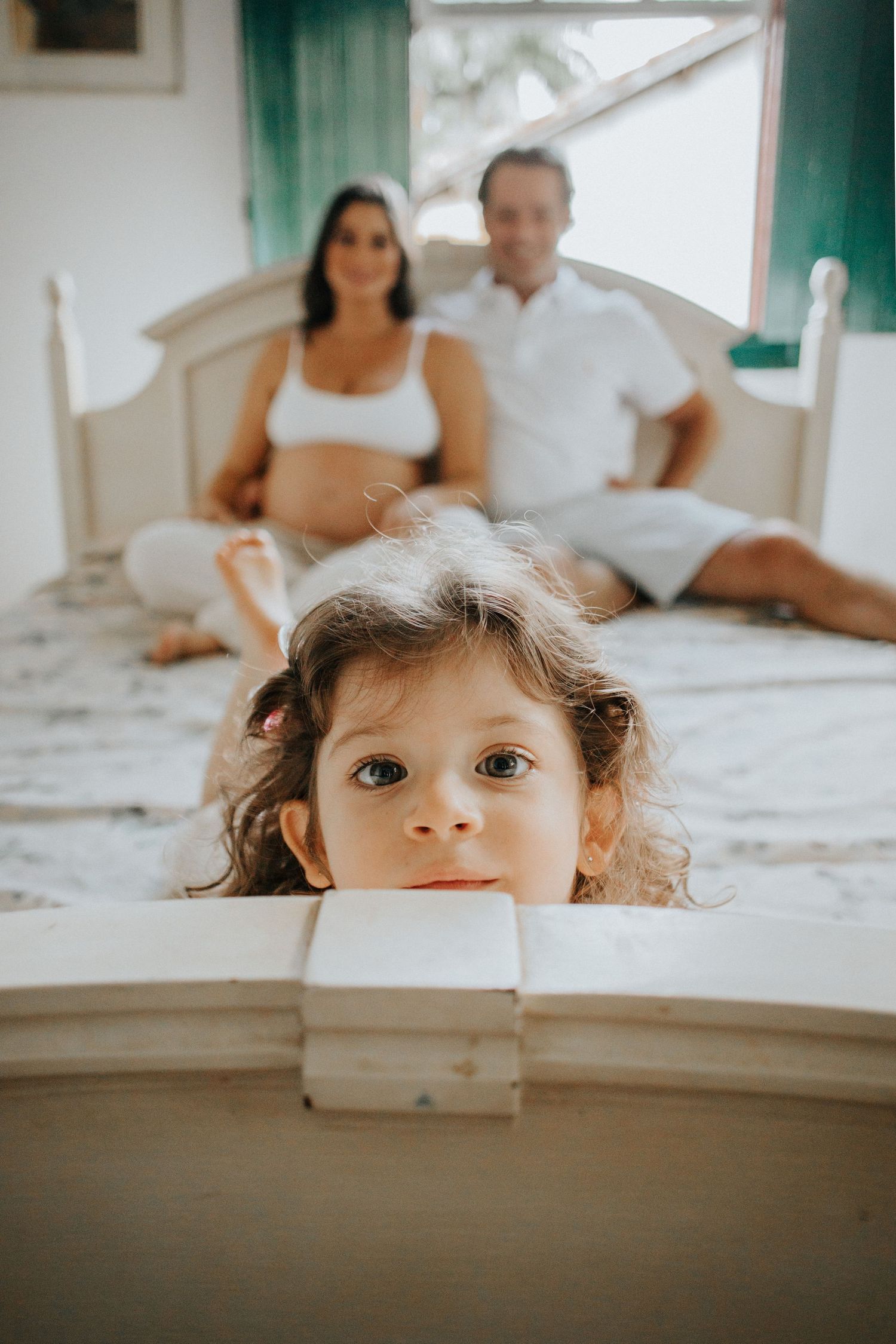 Four candid lifestyle family photos show sweet peekaboo moments with a young child peeking over a white counter.