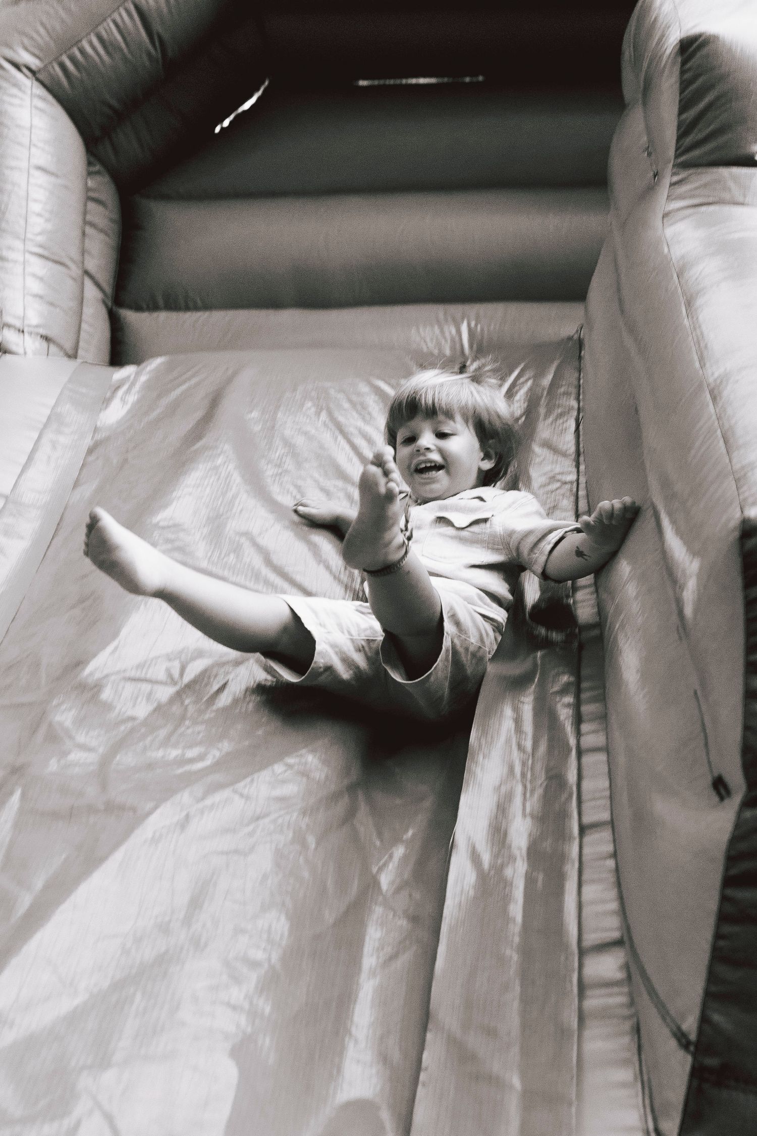 A sequence of black and white photos showing a person climbing up and over a white inflatable wall or barrier.