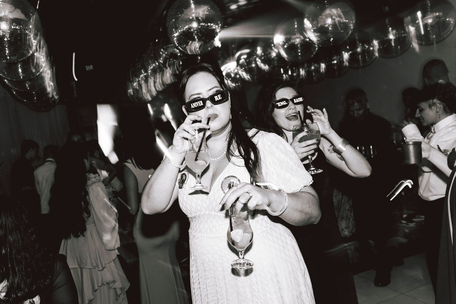 Black and white photo of party guests enjoying drinks at a vintage celebration.