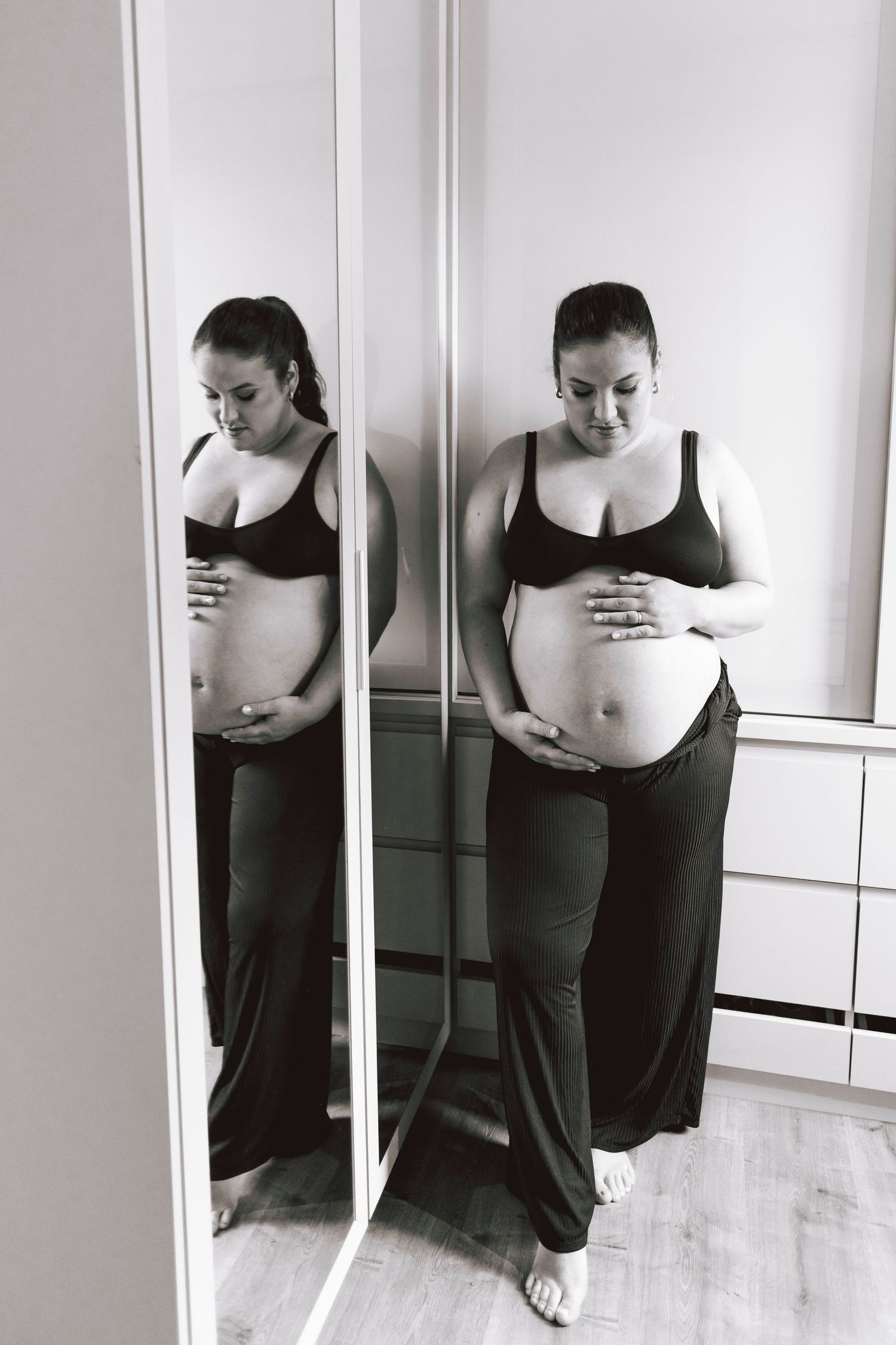 Black and white pregnancy progression photos showing a growing baby bump in silhouette against a white wall.