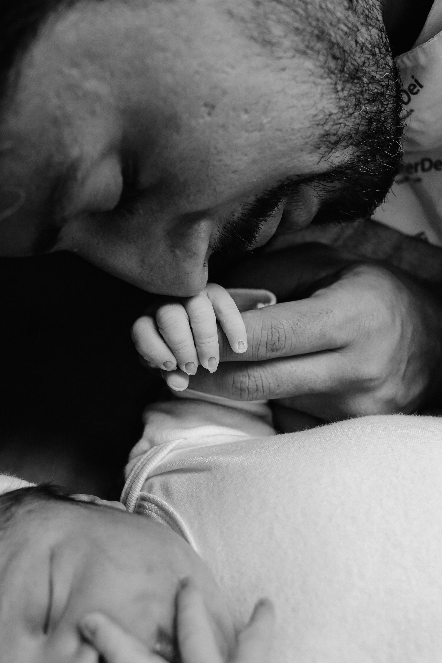 An intimate black and white moment of a tiny hand being held.