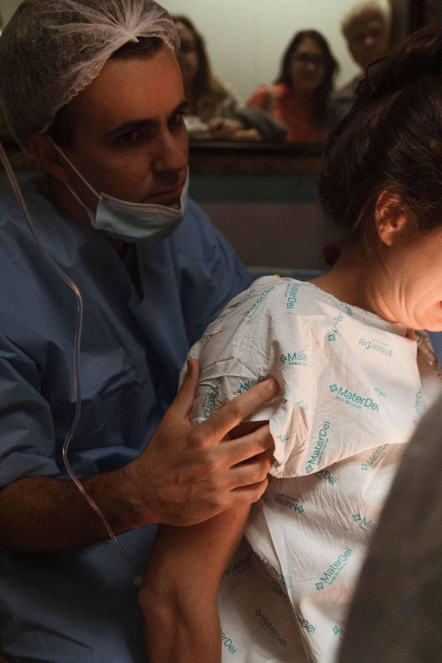 Healthcare provider in scrubs and mask assisting during a medical procedure.