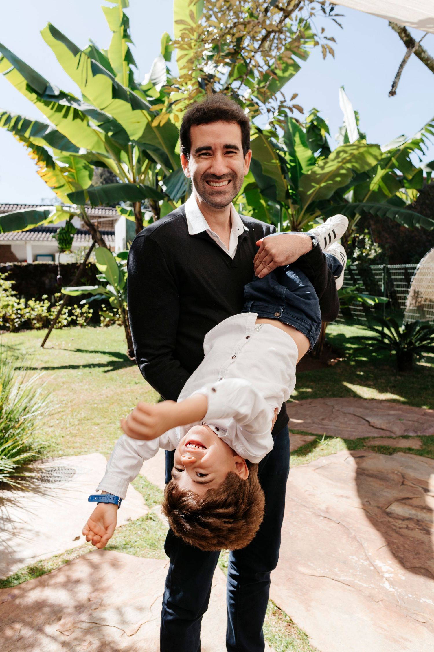 A playful moment captured in a garden setting with tropical foliage in the background.